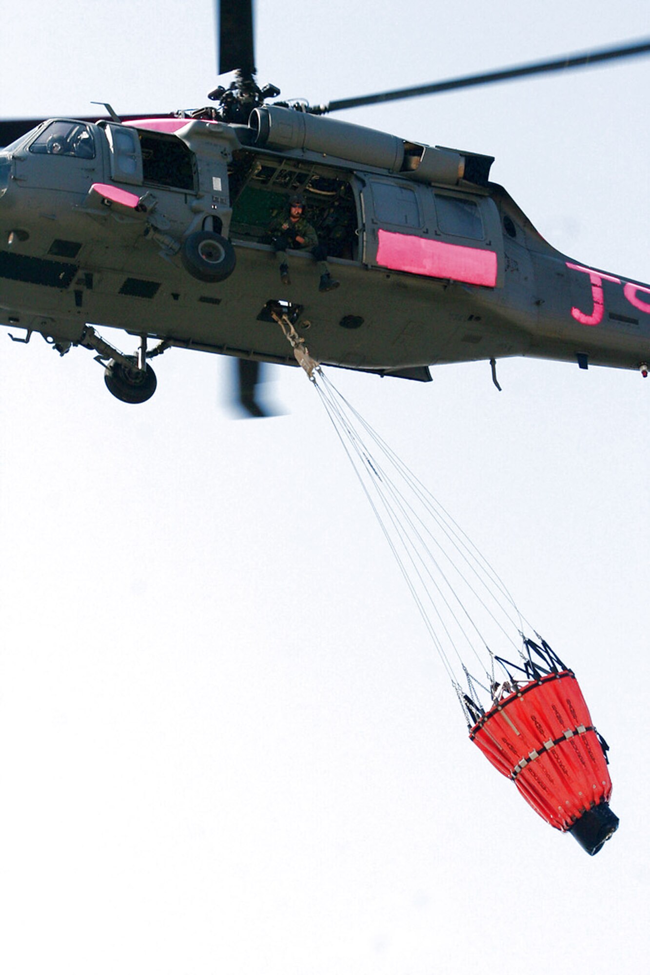 An HH-60G Pave Hawk flies with a water bucket attached July 2 near Sacramento, Calif. The aircrews trained with water buckets to become certified for firefighting suppression duty. The HH-60G is from the 129th Rescue Wing of the California Air National Guard. (U.S. Air Force photo/Master Sgt. Barbara Apkarian) 
