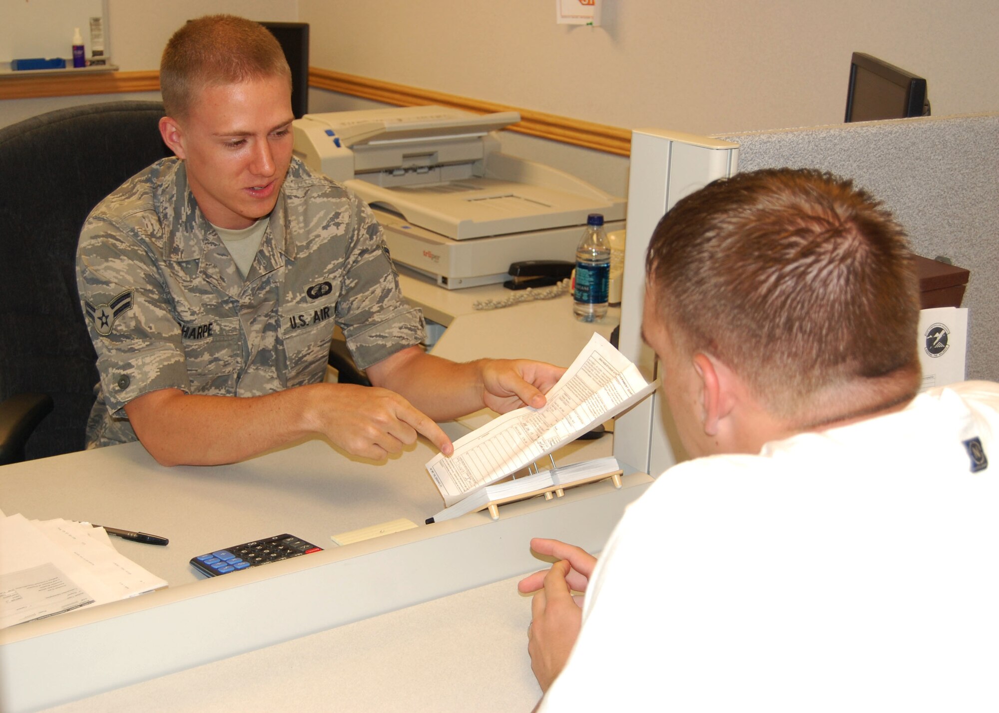 Airman 1st Class Robert Sharpe, 341st Comptroller Squadron customer service technician, assists an Airman with a military pay question at building 1191 July 7. The 341st CPTS and 341st Contracting Squadron merge into the 341st Contracting and Comptroller Squadron at a ceremony July 11. The merger is intended to be seamless for base personnel and people can continue to visit the finance customer service office for all military-related pay questions.  (U.S. Air Force photo/Senior Airman Eydie Sakura)