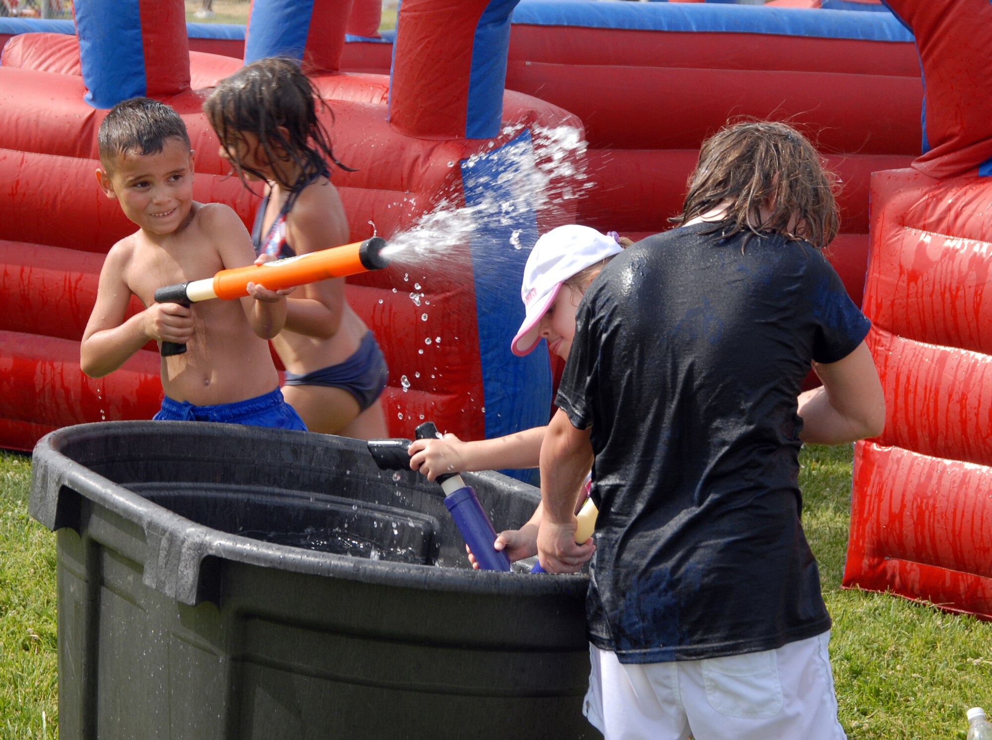 Children participate in a water gun fight during the Summer Bash at Robert and Wings Field here July 4. Summer Bash featured rides, music, food, drinks, games and fireworks. (Air Force photo by Airman 1st Class William O’Brien)