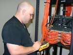 Gregory Campbell, a network data communication analyst at the Air Force Personnel Center on Randolph Air Force Base, Texas, verifies cable ports for the new operation center?s network switch recently. The switch's components feed down from a secure server and will give AEF workers secure lines once the operation center is fully operational. Since November 2007, more than 12,000 feet of combined fiber optic and copper cables have been placed in the new center. (U.S. Air Force photo by Richard Salomon) 