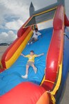 Richard Alvaravo and Brandon Gilbert glide down an inflatable slide during the Randolph Air Force Base Independence Day celebration. Randolph Air Force Base shared Independence Day with the local community and hosted two bands, festive foods, several activities and fireworks on the south ramp. (U.S. Air Force photo by Steve White)