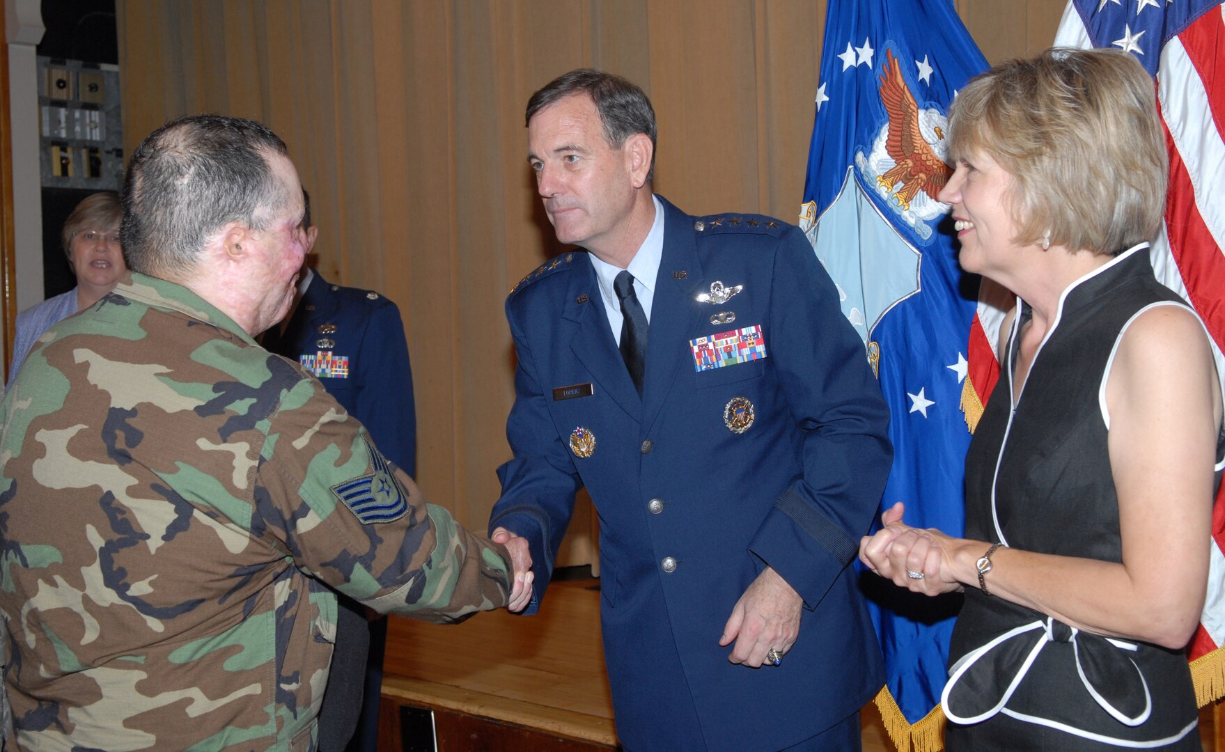 Gen. Stephen Lorenz, Commander of Air Education and Training Command, passes his new coin to Tech. Sgt. Israel Del Toro, a tactical air control party member injured while serving in Afghanistan, after the AETC change of command ceremony July 3 as his wife, Leslie, looks on. (U.S. Air Force photo by Rich McFadden)