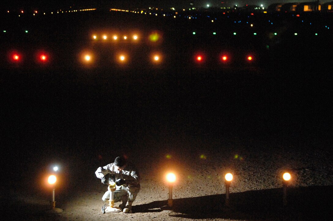 JOINT BASE BALAD, Iraq -- Staff Sgt. Samnang Lay, 332nd Expeditionary Civil Engineer Squadron electrician, replaces a bulb on an approach light here, July 5. Illumination of the airfield at night is critical to the safety of aircraft, personnel and cargo at the busiest single runway operation in the Department of Defense. Sergeant Lay is deployed from Ellsworth Air Force Base, S.D. (U.S. Air Force photo/ Senior Airman Julianne Showalter)