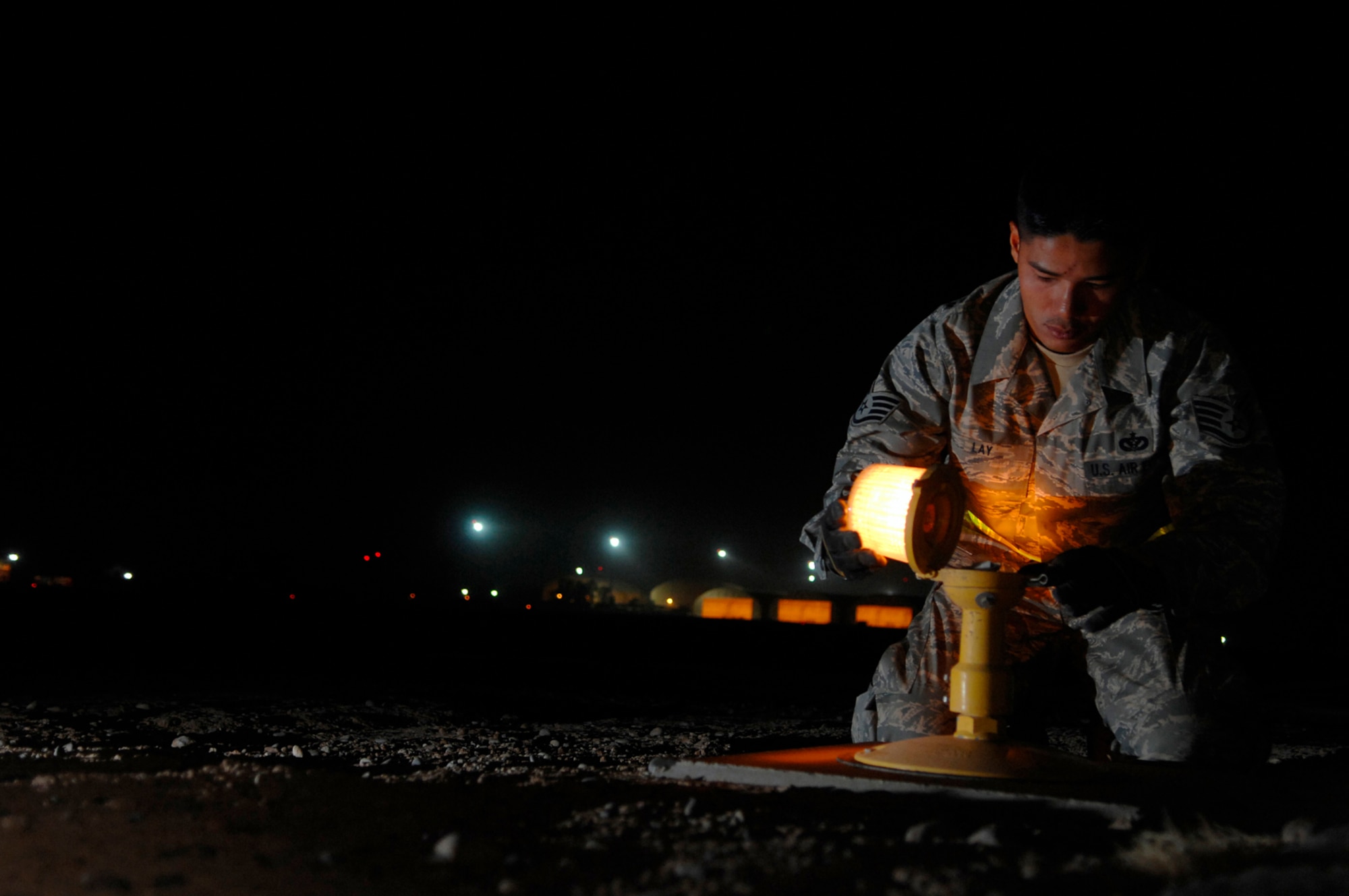 JOINT BASE BALAD, Iraq -- Staff Sgt. Samnang Lay, 332nd Expeditionary Civil Engineer Squadron electrician, replaces a bulb on a runway edge light here, July 5. The airfield lights safely guide aircraft during taxi, take off and landing during inclement weather and nighttime operations. Sergeant Lay is deployed from Ellsworth Air Force Base, S.D. (U.S. Air Force photo/ Senior Airman Julianne Showalter)