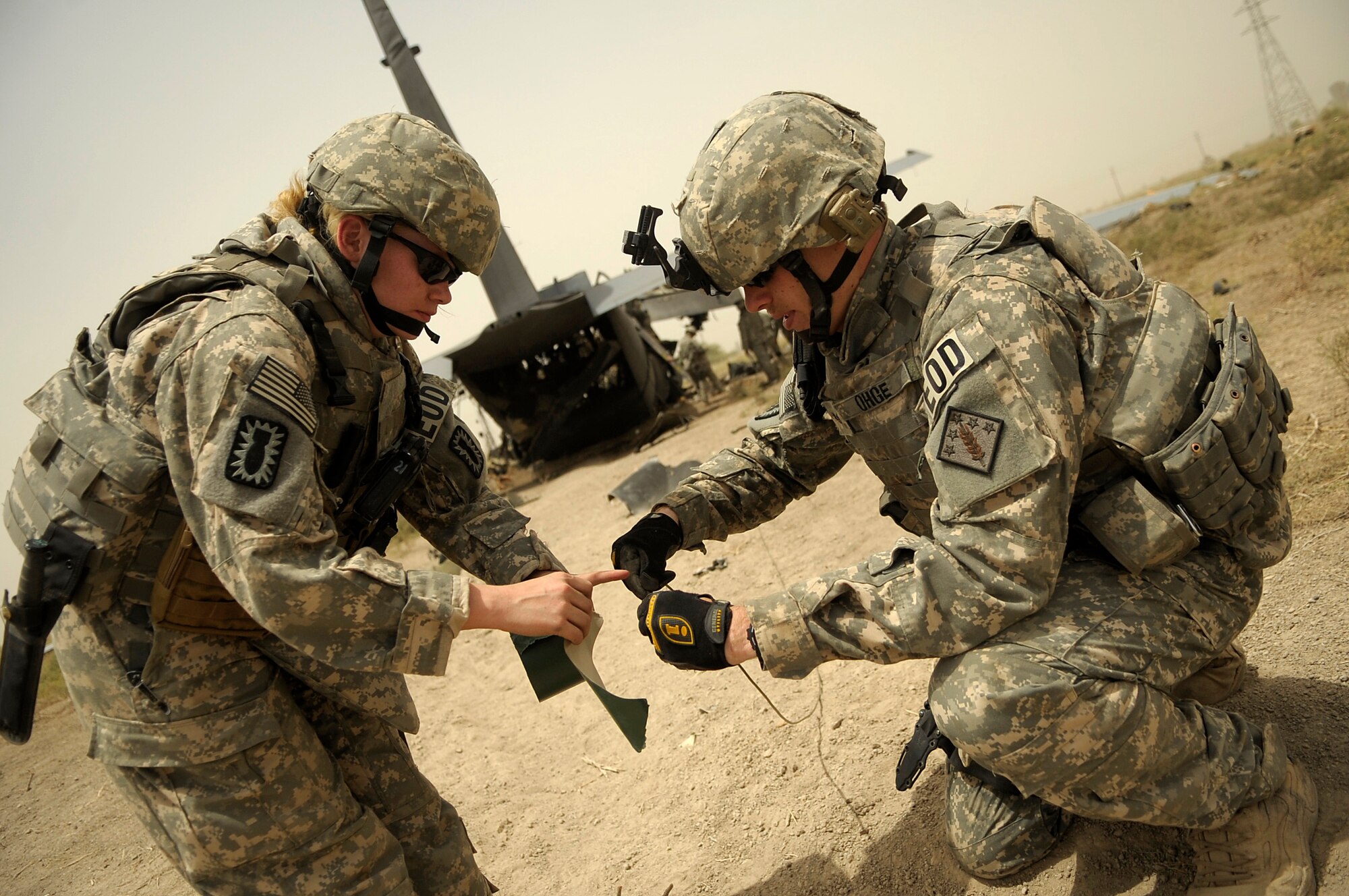 BAGHDAD, Iraq -- Senior Airman Kimberly Pate (left) and Staff Sgt. Stephen Oghe  from the 447th Expeditionary Civil Engineer Squadron's explosive ordinance disposal team prepare detonation cord after placing explosive charges around the aft section of a C-130 Hercules here July 7. The EOD team is using a series of controlled detonations that are designed to divide the airplane into smaller pieces so it can be moved. The C-130 made an emergency landing in a field north of Baghdad International Airport shortly after take-off June 27. (U.S. Air Force photo/Tech. Sgt. Jeffrey Allen)