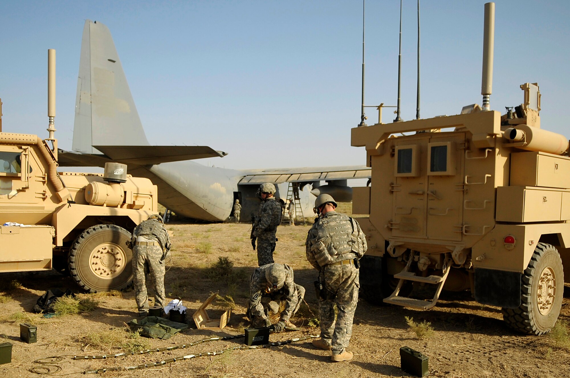 BAGHDAD, Iraq -- Explosive Ordinance Disposal personnel from the 447th Expeditionary Civil Engineer Squadron at Sather Air Base, Iraq, prepare explosives before placing them on the wings of a C-130 Hercules here July 7. The EOD team is using a series of controlled detonations designed to divide the airplane into smaller pieces so it can be moved.  The C-130 made an emergency landing in a field north of the Baghdad International Airport shortly after take-off June 27.  (U.S. Air Force photo/Tech. Sgt. Jeffrey Allen)