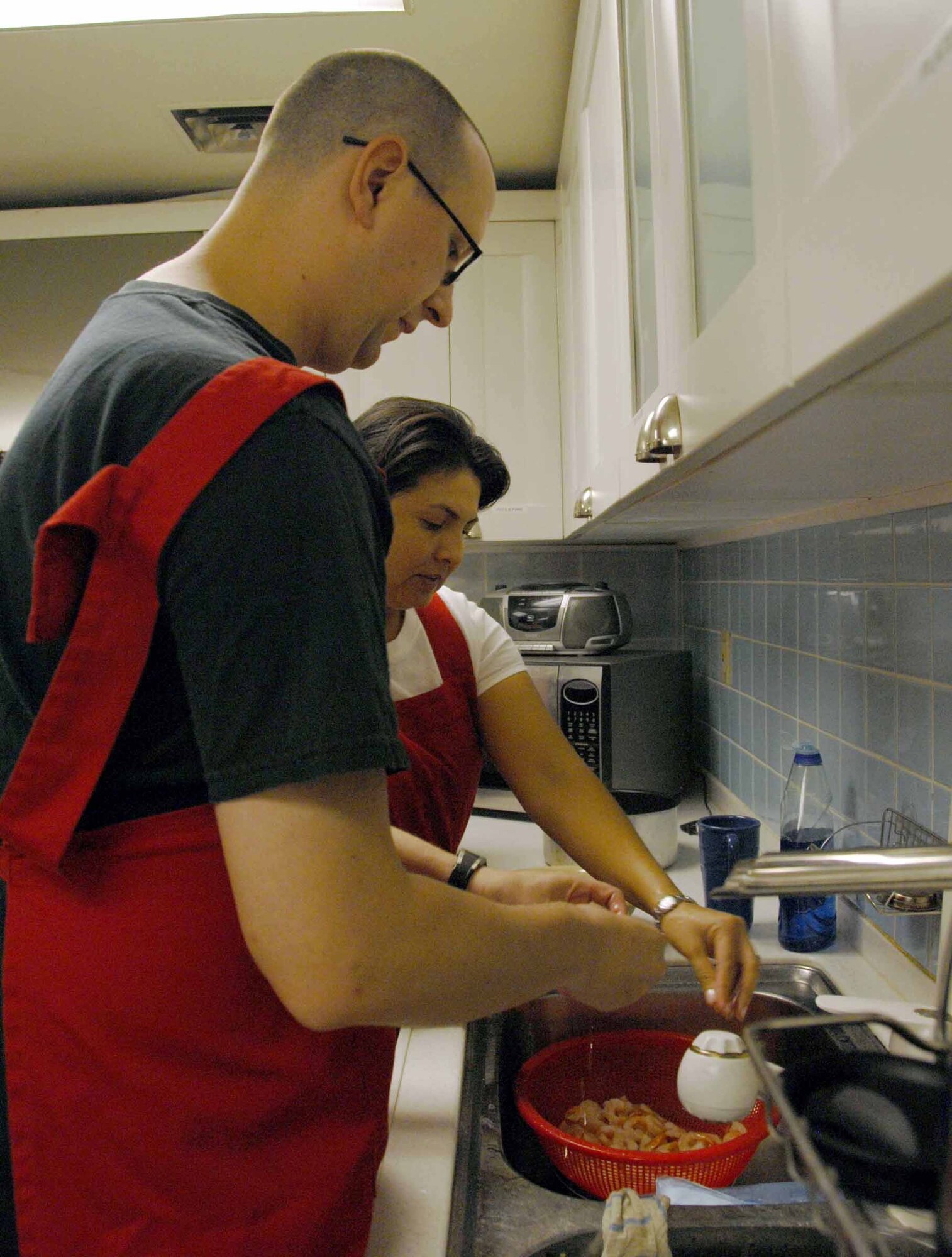 OSAN AIR BASE, Republic of Korea -- (From left to right) Senior Airman Matthew Garrett, 51st Munitions Squadron conventional support member, and Staff Sgt. Jobette Rosati, 51st Fighter Wing military justice paralegal, peel shrimp as part of the  Cajun cooking class held July 1 at the Airman and Family Readiness Center. The Cajun cooking class is just one of several cooking class hosted by the AFRC. (U.S. Air Force photo/Staff Sgt Lakisha Croley)