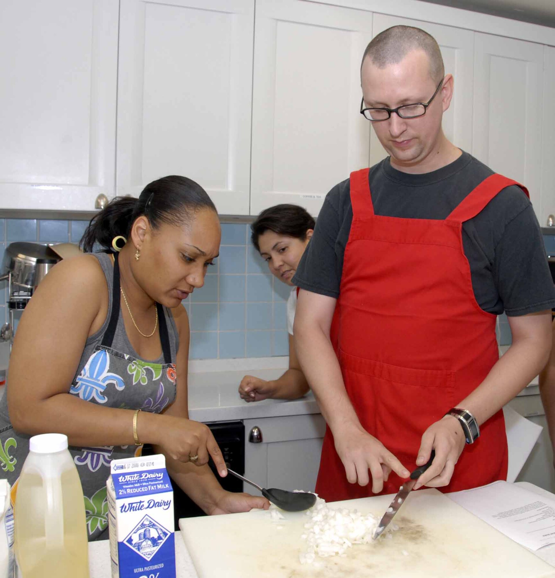 OSAN AIR BASE, Republic of Korea – Tech. Sgt. Danielle Speck, (left), Cajun cooking class instructor, prepares to add Senior Airman Matthew Garrett’s chopped onions to the Cajun stew her students are preparing during the during the Cajun class held July 1 at the Airman and Family Readiness Center. The AFRC is host to several different classes and activities, including cooking classes, volunteer opportunities, and cultural trips. Sergeant Speck is a readiness manager with the 51st Logistics Readiness Squadron. Airman Garrett is assigned to the 51st Munitions Squadron. (U.S. Air Force photo/Staff Sgt Lakisha Croley)