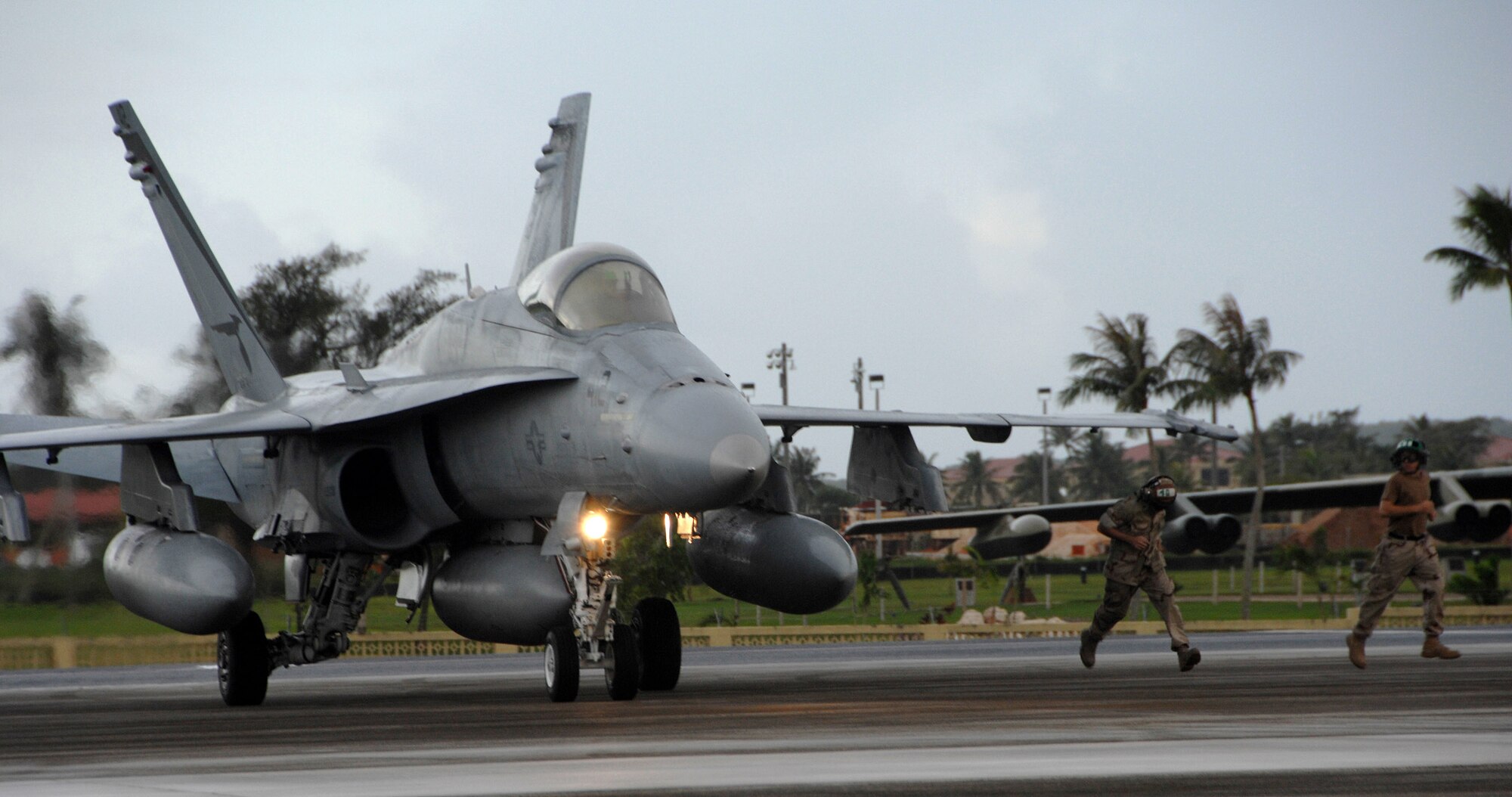 Air Force Airmen guide a U.S. Navy F/A-18 Hornet into place on Andersen Air Force Base, July 9. The F/A-18 is a strike fighter aircraft flown by VFA-94. The aircraft was one of 12 F/A-18's laying-over at Andersen until July 11 when they will leave for Royal Australian Air Force Base Tindal to participate in an exercise with the Australians. (U.S. Air Force photo by Airman 1st Class Courtney Witt)