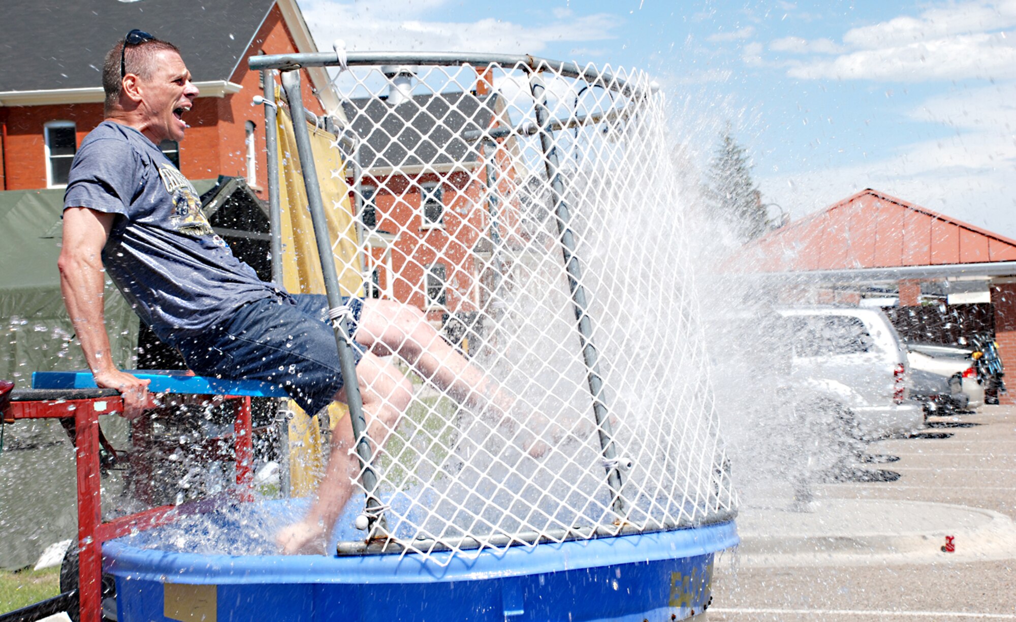 Master Sgt. Todd Preston, 30th Airlift Squadron first sergeant, kicks water toward children during the Block Party June 20. The children, instead of throwing tennis balls, ran to and from the switch to dunk Sergeant Preston. The Rising 6 organization sponsored the event. Along with the dunk tank, other attractions included a mobile petting zoo, free hamburgers and hotdogs, a vehicle prepared for demolition and musical entertainment. The event took place behind dorms 223 through 228.