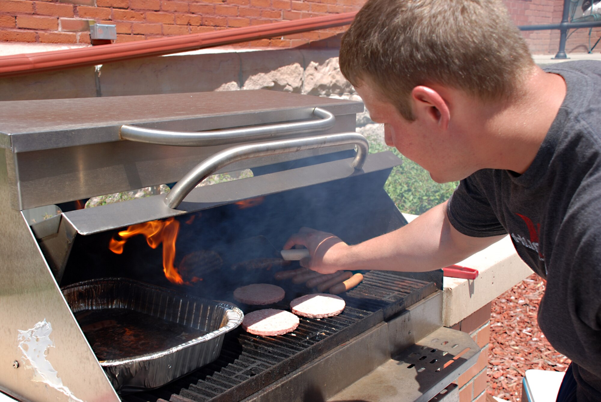 Senior Airman Jon Beier, 90th Missile Maintenance Squadron, prepares hamburgers and hotdogs at lunchtime during the Block Party. Airman Beier, as well as many others, volunteered to be a cook for the event.