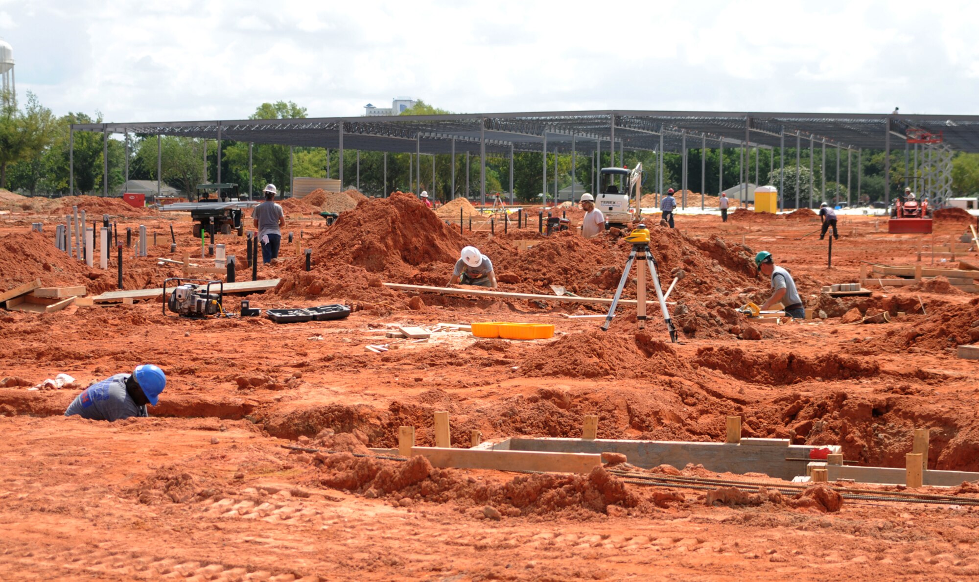 The steel framework of the new commissary rises in the background, while mounds of red clay are being removed, footings are being poured and below-slab plumbing and electrical lines are being installed for the new base exchange in the foreground, June 26.  The expected completion date for the new facilities, replacing those destroyed by Hurricane Katrina almost three years ago, is Nov. 14, 2009.  (U.S. Air Force photo by Kemberly Groue)
