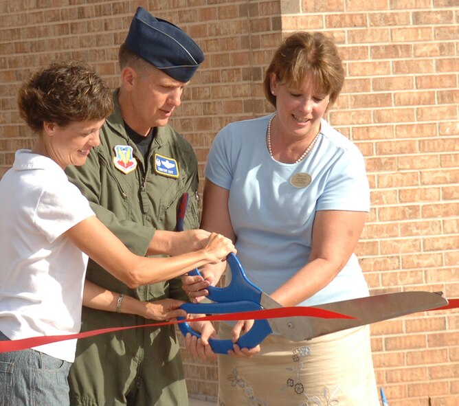 DYESS AIR FORCE BASE, Texas -- Col. Timothy Ray, 7th Bomb Wing commander, is assisted by his wife, Rhonda (left), and Diane Areskog, 7th Force Support Squadron youth director, during the ribbon cutting ceremony of the renovated Dyess Youth Center Wednesday, July 9. The Youth Center has been undergoing renovations and expansion construction since October 2006. Construction of the facility is expected to be completed next month. The original facility was 13,794 square feet. The construction increased the total square footage to 32,551 square feet. Total cost of the construction was approximately $4.4 million. Some of the renovated areas include a computer room, teen center, music room, and game room. The new construction included the addition of a School Age Program reception area, classrooms, commercial kitchen, snack bar, common areas, and improved communication, safety and security equipment. (Air Force photo by Airman 1st Class Micheal Breaux) 