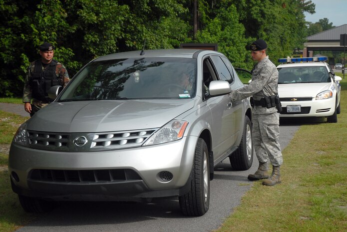 Airman 1st Class Dustin Miller checks the license and registration of a Team Charleston motorist while Tech. Sgt. James Sanscrainte maintains an overwatch position. The 437th Security Forces Squadron is taking a more proactive approach in citing violators who fail to adhere to base vehicle laws regarding use of cell phones and seat belts. Airman Miller and Sergeant Sanscrainte are patrolmen assigned to the 437 SFS. (U.S. Air Force photo/Senior Airman Sam Hymas)
