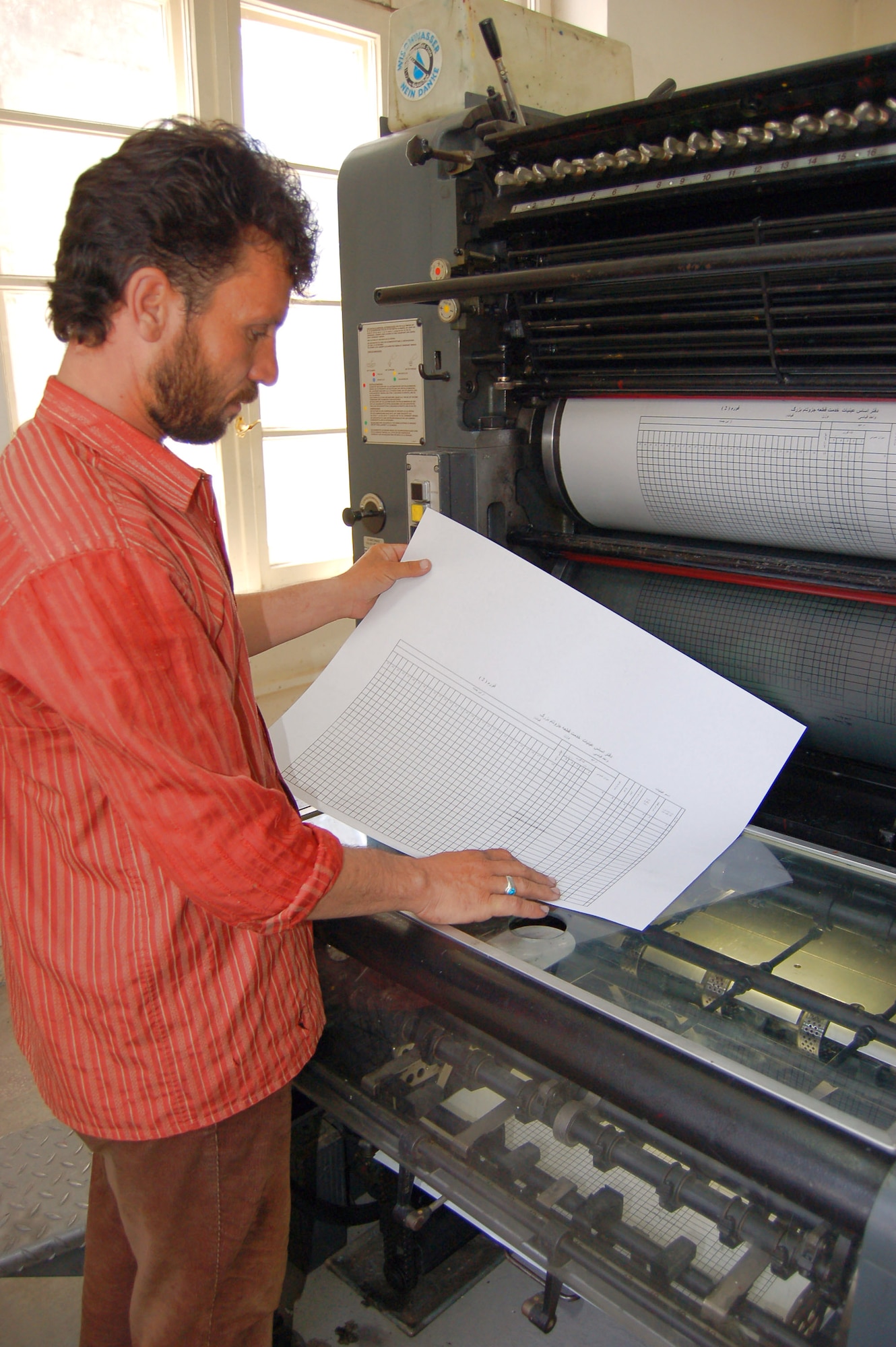 An Afghan National Army civilian inspects a product made at the ANA print plant in Kabul, Afghanistan. During an average week, the plant produces more than 75,000 products used for training, recruitment and logistical support. (U.S. Air Force photo/Staff Sgt. Beth Del Vecchio)