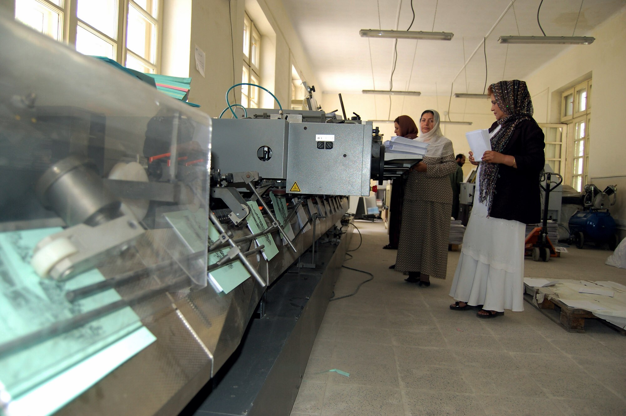 Afghan National Army civilians load lined paper into a post-press machine at the ANA print plant in Kabul, Afghanistan. During an average week, the plant produces more than 75,000 products used by the ANA for training, recruitment and logistical support. (U.S. Air Force photo/Staff Sgt. Beth Del Vecchio)