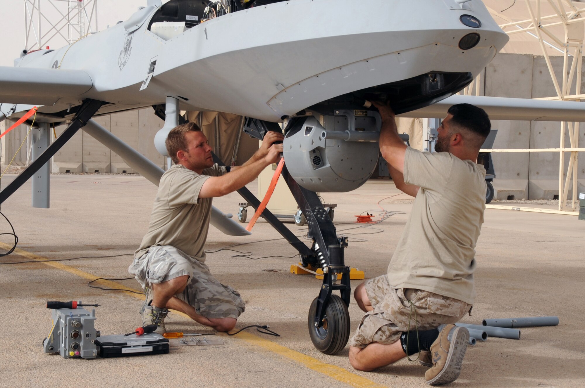 ALI BASE, Iraq -- Paul Rudolph an aircraft mechanic and Schuyler Dunn an aircraft technician of the 361st Expeditionary Reconnaissance Squadron, replaces a Multispectural Targeting System Ball on the Predator MQ-1B Unmanned Aerial Vehicle here July 9. Through the use of advanced capabilities, focused doctrine and detailed training the predator provides integrated and synchronized close air combat operations, to include intelligence, surveillance and reconnaissance. (U.S. Air Force photo/Tech. Sgt. Sabrina Johnson)