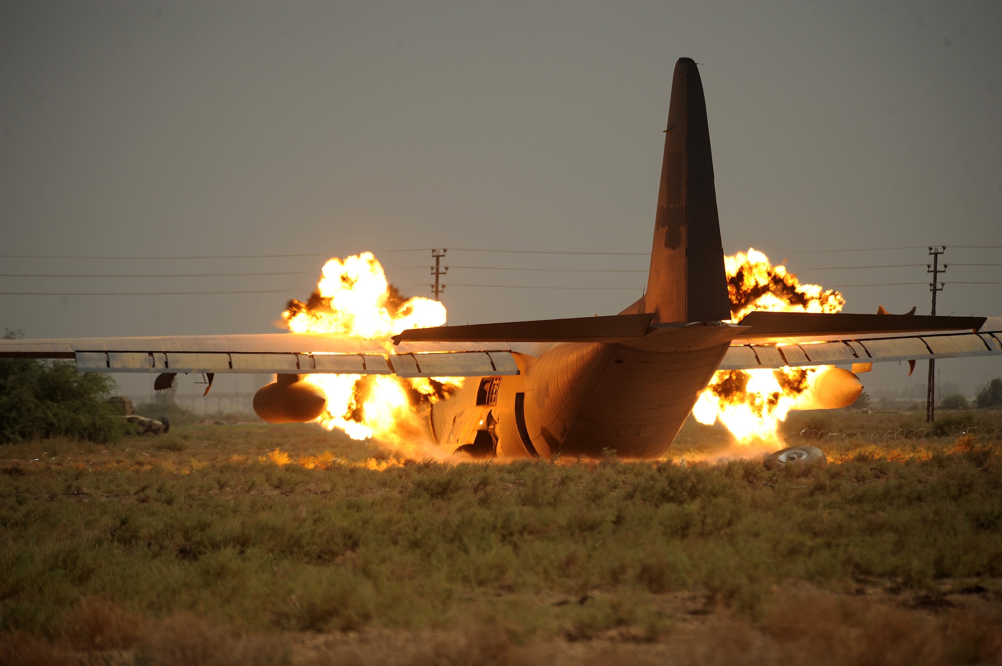 BAGHDAD, Iraq -- Explosive Ordinance Disposal personnel from the 447th Expeditionary Civil Engineer Squadron at Sather Air Base, Iraq, detonate explosives to detach the wings from the body of a C-130 Hercules here July 7. The EOD team is using a series of controlled detonations designed to divide the airplane into smaller pieces so it can be easily moved. The C-130 made an emergency landing in a field north of Baghdad International Airport shortly after take-off June 27. (U.S. Air Force photo/Tech. Sgt. Jeffrey Allen)