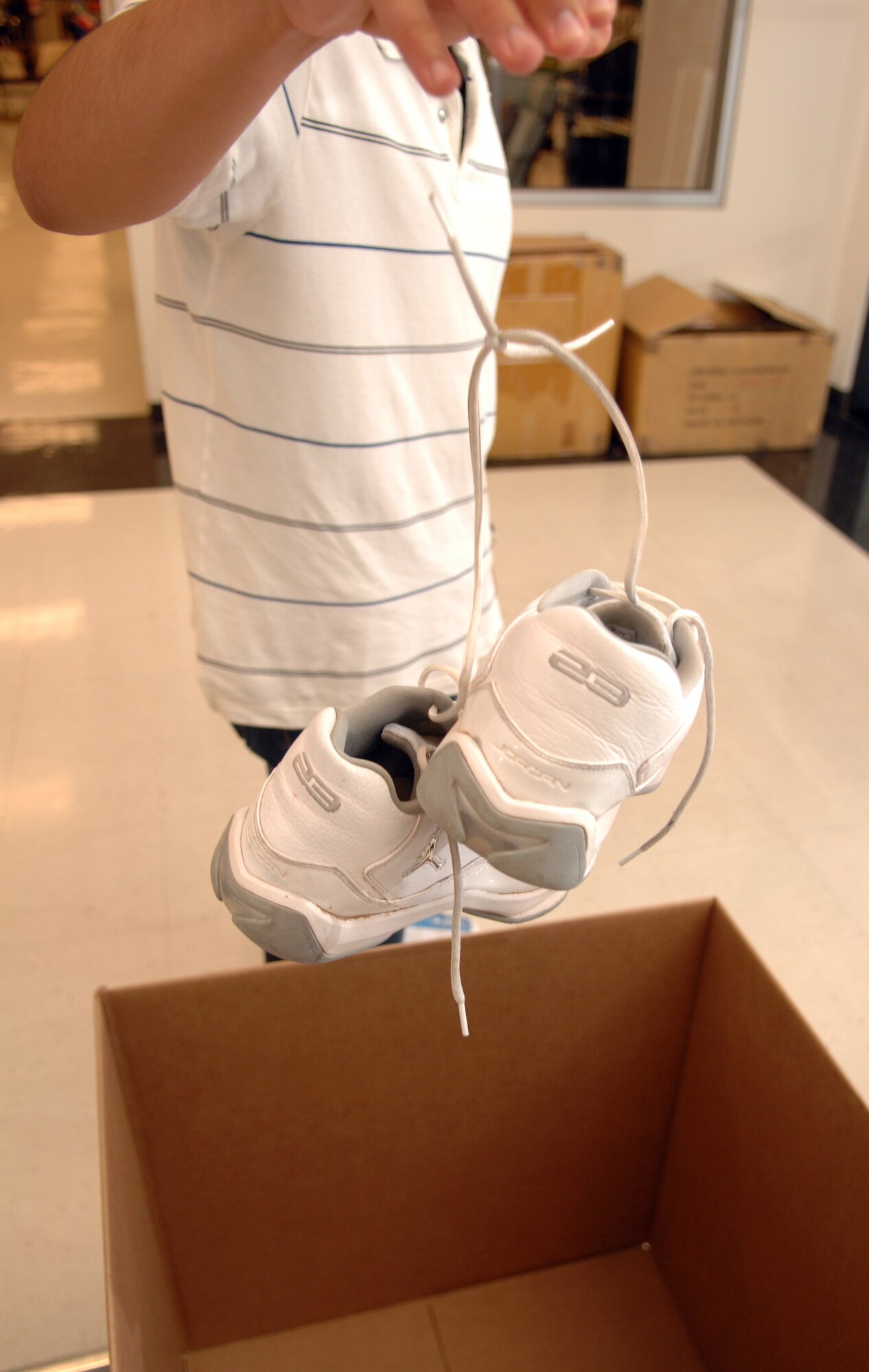 Airman 1st Class Martin Rodriguez, 49th Comptroller Squadron, drops his old shoes in a collection box at the Base Exchange at Holloman Air Force Base, N.M., June 29. The BX is one of three collection points for the base shoe drive along with the base chapel and Military Personnel Flight here. There is also a box located in every squadron.