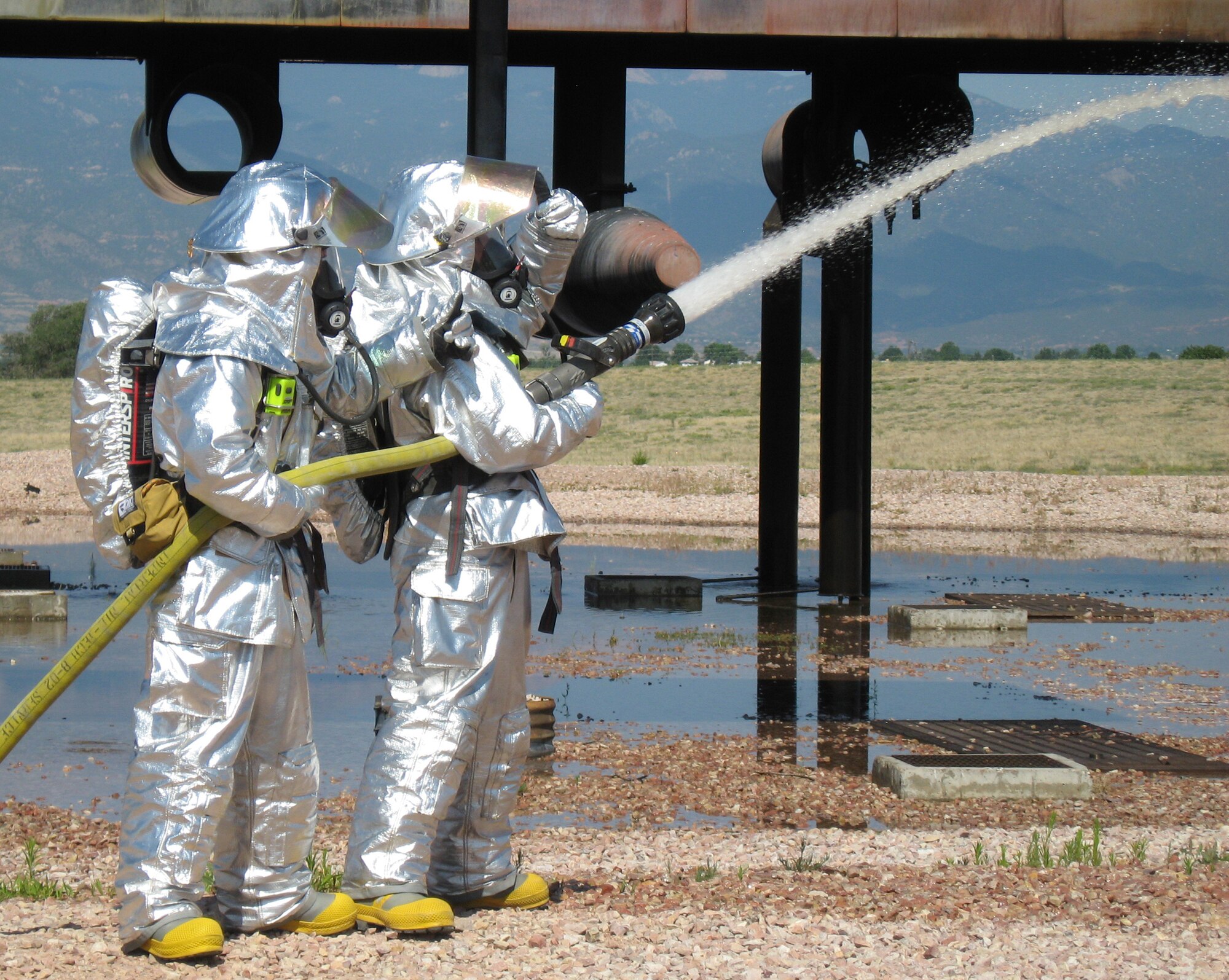 Members of the 21st Civil Engineer Squadron Fire Protection Flight practice their skills on a C-130 mock-up July 10 at Peterson Air Force Base, Colo. The flight conducts these exercises periodically throughout the year to maintain their fire fighting proficiency. (U.S. Air Force photo/1st Lt. Brennan Howell)
