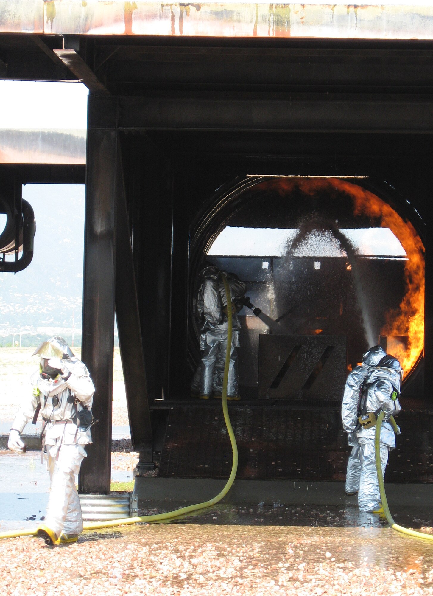 Members of the 21st Civil Engineer Squadron Fire Protection Flight practice their skills on a C-130 mock-up July 10 at Peterson Air Force Base, Colo. The flight conducts these exercises periodically throughout the year to maintain their fire fighting proficiency. (U.S. Air Force photo/1st Lt. Brennan Howell)
