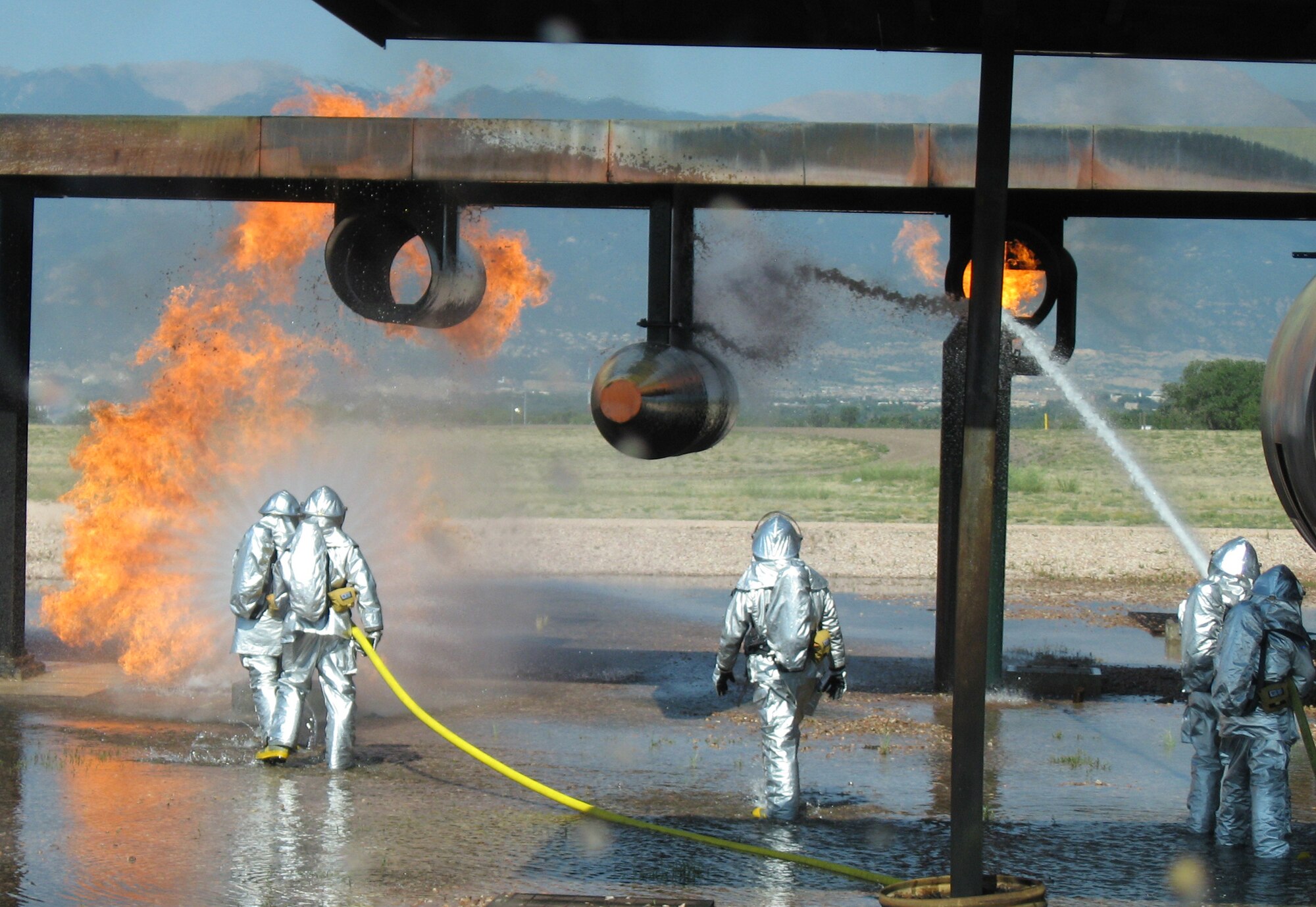 Members of the 21st Civil Engineer Squadron Fire Protection Flight practice their skills on a C-130 mock-up July 10 at Peterson Air Force Base, Colo. The flight conducts these exercises periodically throughout the year to maintain their fire fighting proficiency. (U.S. Air Force photo/1st Lt. Brennan Howell)

