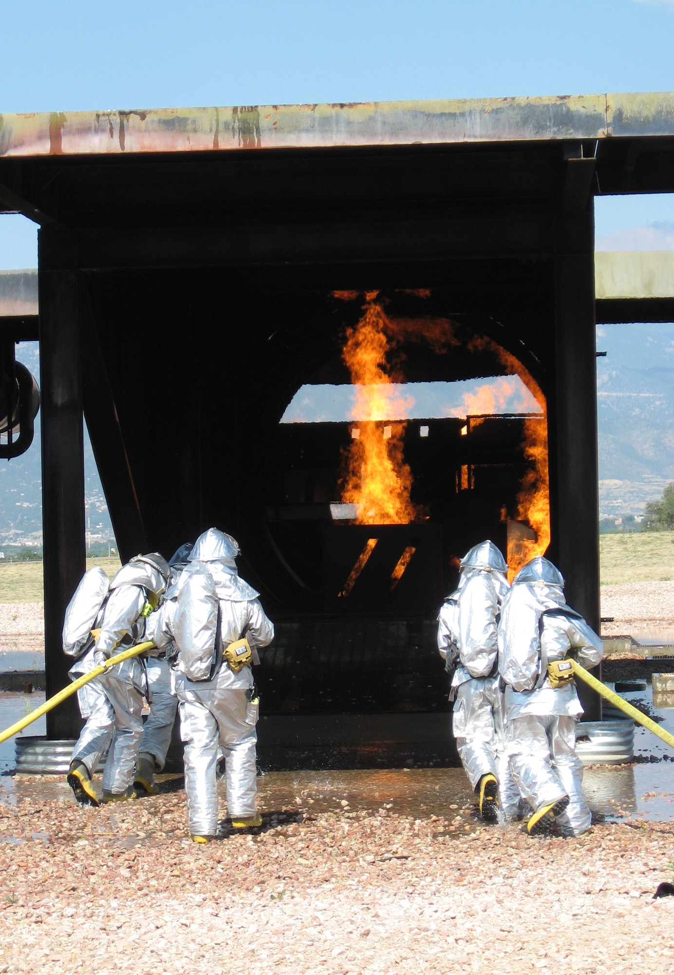Members of the 21st Civil Engineer Squadron Fire Protection Flight practice their skills on a C-130 mock-up July 10 at Peterson Air Force Base, Colo. The flight conducts these exercises periodically throughout the year to maintain their fire fighting proficiency. (U.S. Air Force photo/ 1st Lt. Brennan Howell)
