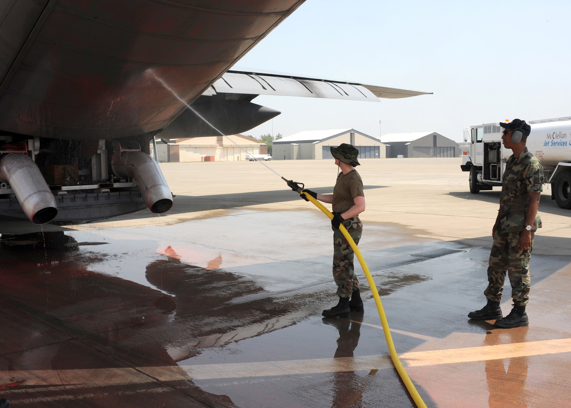 Senior Master Sgt. Aaron Smith watches for safety issues as an Airman washes fire retardant off the cargo doors of a C-130 Hercules equipped with the modular airborne fire fighting system at McClellan Airfield, Calif., July 8. Sergeant Smith's job is to ensure Airmen and equipment are safe during firefighting operations. The 153rd AW is conducting firefighting operations as part of the 302nd Air Expeditionary Group. Sergeant Smith is assigned to the 153rd Airlift Wing of the Wyoming Air National Guard. (U.S. Navy photo/Petty Officer First Class Steven J. Weber)