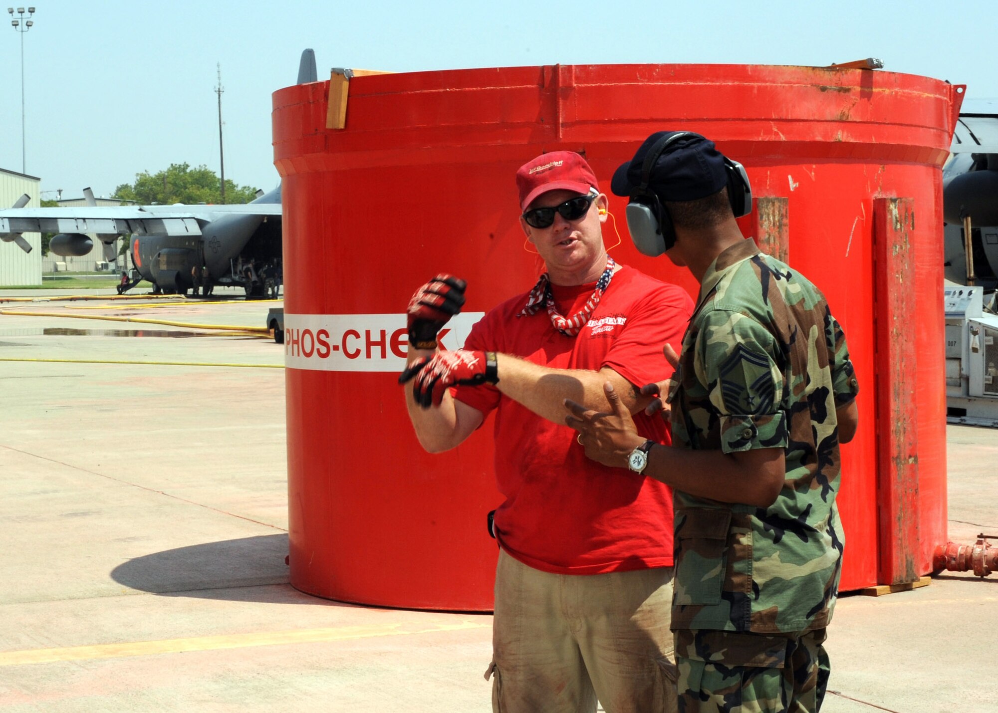 Senior Master Sgt. Aaron Smith discusses fire retardant reloading operations with a civilian representative from the retardant supply company at McClellan Airfield, Calif., July 8. Sergeant Smith is assigned to the 153rd Airlift Wing of the Wyoming Air National Guard. (U.S. Navy photo/Petty Officer First Class Steven J. Weber)