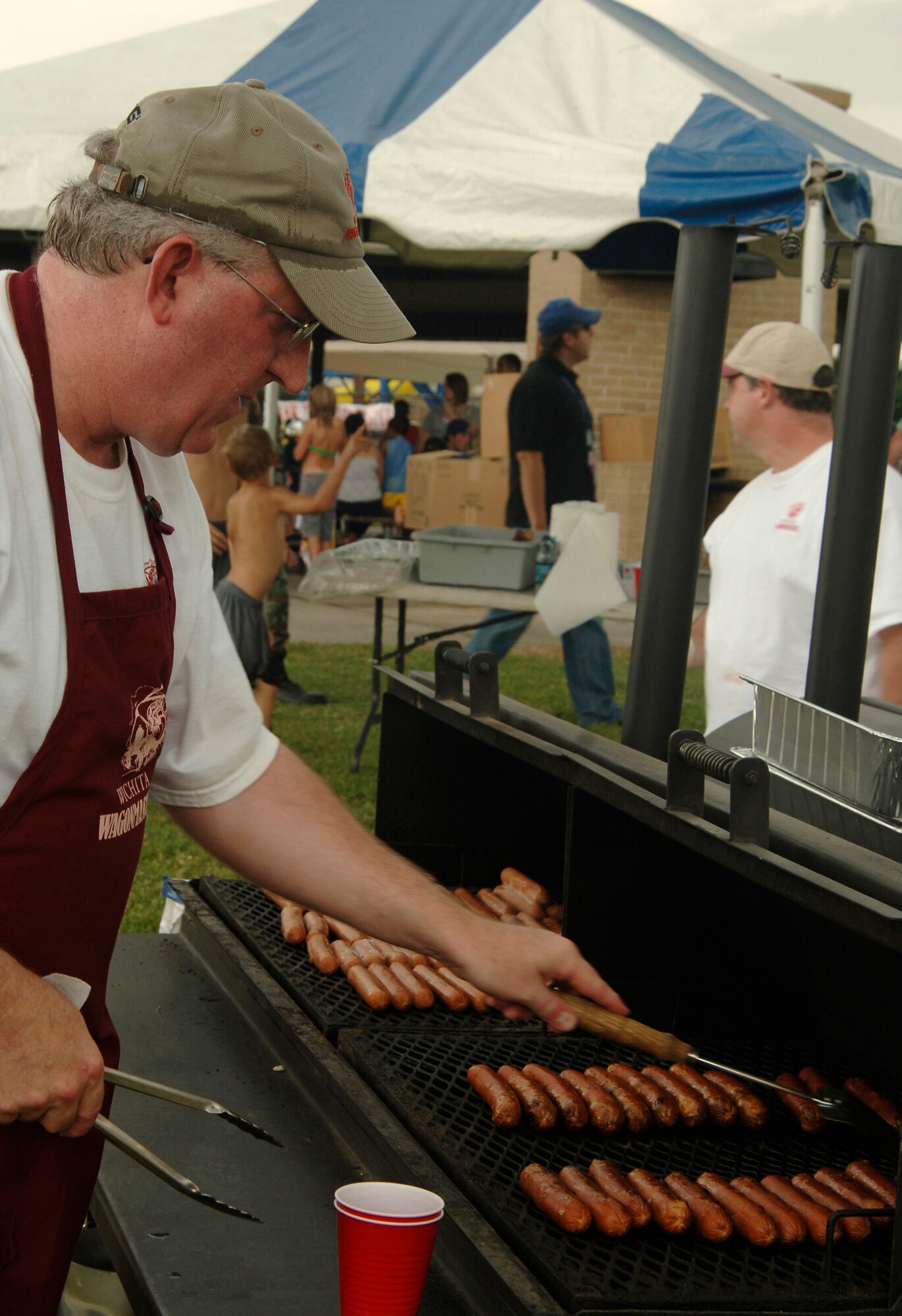 MCCONNELL AIR FORCE BASE, Kan. -- Wagonmaster’s member, Scott Hampel, cooks hot-dogs for the 22nd Services Squadron beach party, July 2. “We appreciate the opportunity to come out here and cook for the servicemen and women” said Bill Frailey, another Wagonmaster member. (Photo by Senior Airman Laura Suttles)