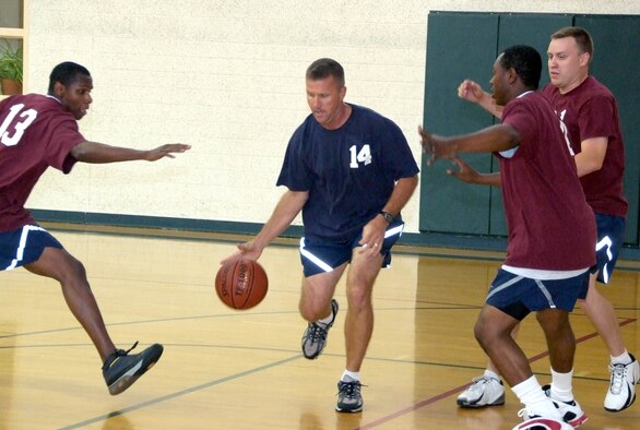 Lt. Col. Mark Batcho, 14, dribbles pass members of the base-populous team during the Commander’s Challenge basketball game held Wednesday, July 9, in the reopened Fitness Center gymnasium at Vance AFB, Okla. Even a new air-conditioning system didn’t help the commanders team. They suffered a loss of 44-38. (U.S. Air Force photo by Terry Wasson)