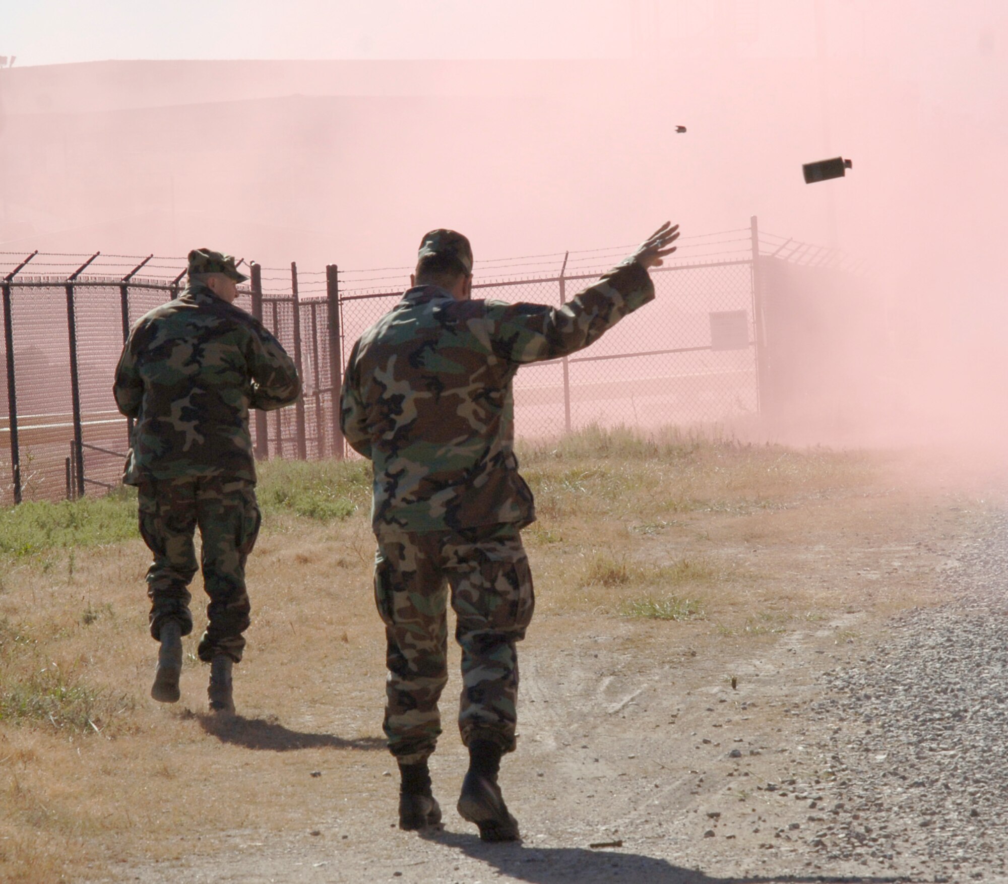 MCCONNELL AIR FORCE BASE, Kan. -- Tech. Sgt. Herschel Brown, 22nd Air Refueling Wing, and Tech. Sgt. John Bryan, 931st Air Refueling Wing, throw red smoke canisters during the Ability to Survive and Operate exercise Nov. 06. Smoke canisters come in multiple colors like red, green and yellow and are used to mainly simulate fire and cover.  (Photo by Senior Airman Roy Lynch)