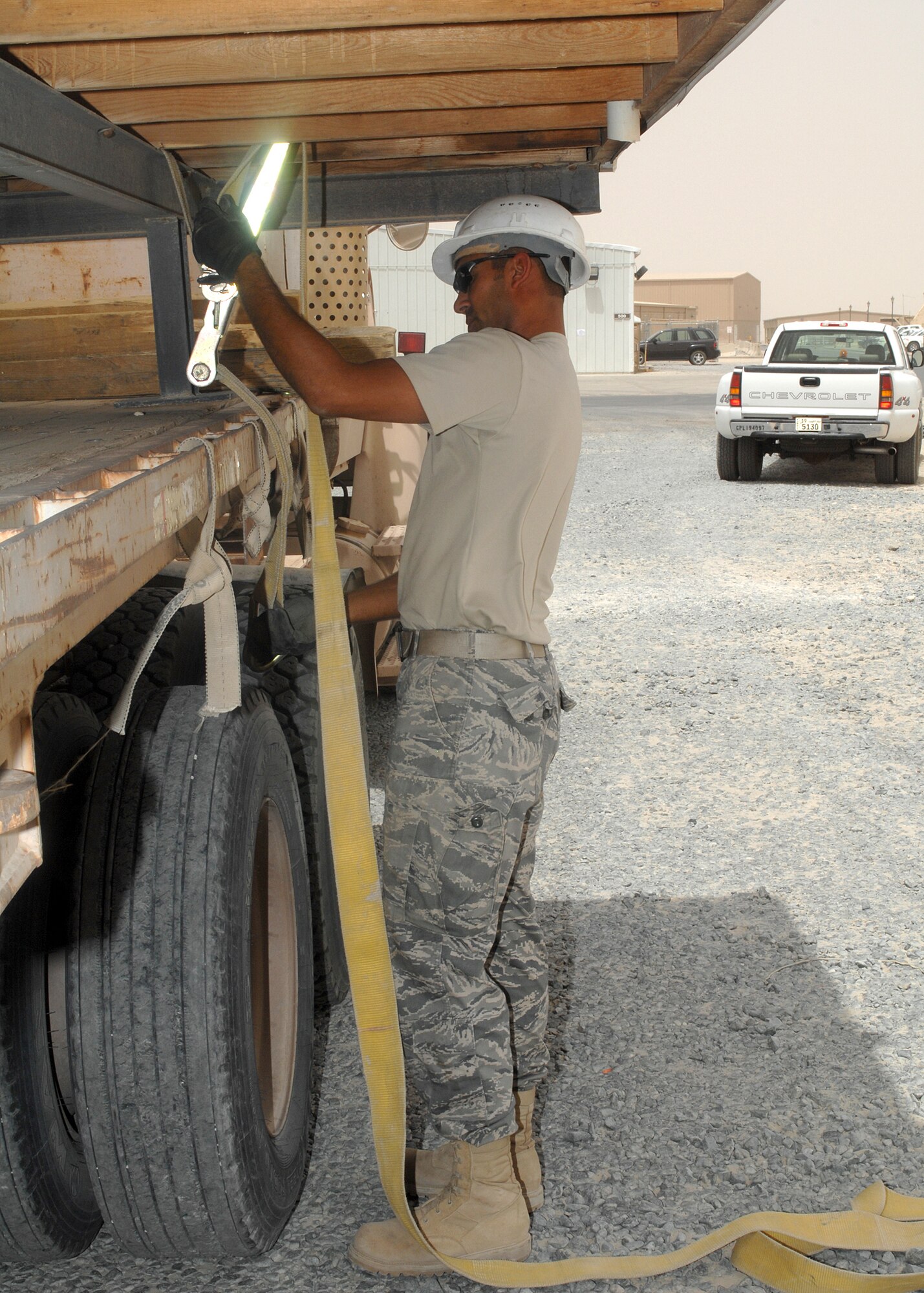 SOUTHWEST ASIA -- Tech. Sgt. Francisco Jimenez, deployed to the 386th Expeditionary Civil Engineer Squadron, uses cargo straps to secure a trailer to a flatbed truck on July 9 at a base in Southwest Asia. The trailer is being moved to the 386th Expeditionary Security Forces squadron K-9 area to increase the square footage of the facility. Sergeant Jimenez is deployed from the Louisiana Air National Guard. (U.S. Air Force photo/Tech. Sgt. Raheem Moore)