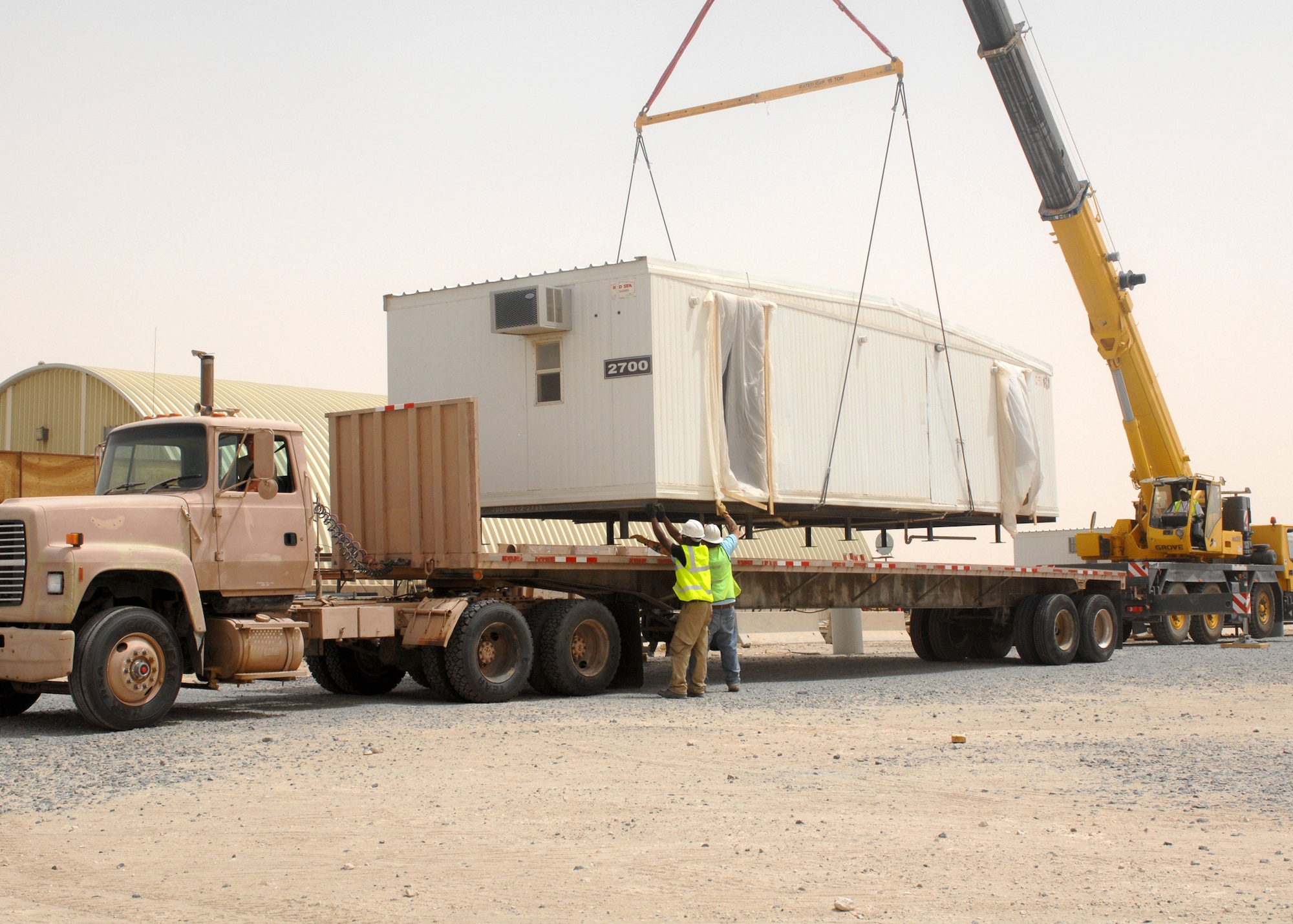 SOUTHWEST ASIA -- Tech. Sgt. Donald Moore, deployed to the 386th Expeditionary Civil Engineer Squadron checks his side mirror as he repositions the flatbed truck while contractors help align the trailer as it's being loaded on July 9 at a base in Southwest Asia. The trailer is being moved to the 386th Expeditionary Security Forces squadron K-9 area to increase the square footage of the facility. Sergeant Moore is deployed from the 186th Air Refueling Wing, Key Field, Miss. (U.S. Air Force photo/ Tech. Sgt. Raheem Moore)