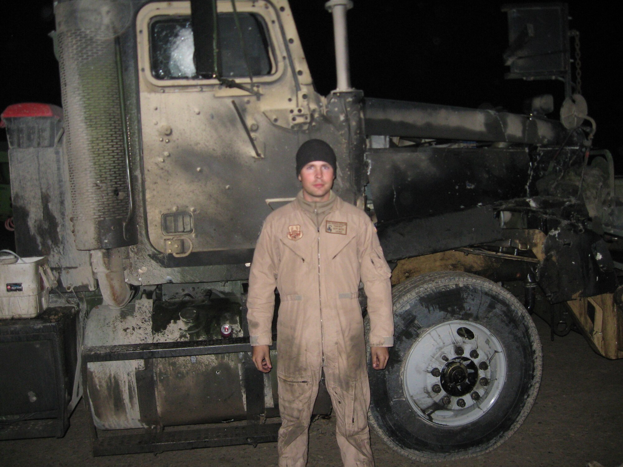 Senior Airman Joshua Bellin, 1st Special Operations Logistics Readiness Squadron, is shown here with the vehicle he was riding in when it was struck by an improvised explosive device in January 2008 in Iraq. Airman Bellin was riding in the passenger seat when the blast occurred and injured him. He was presented a Purple Heart July 8 because of those injuries. (Courtesy photo)