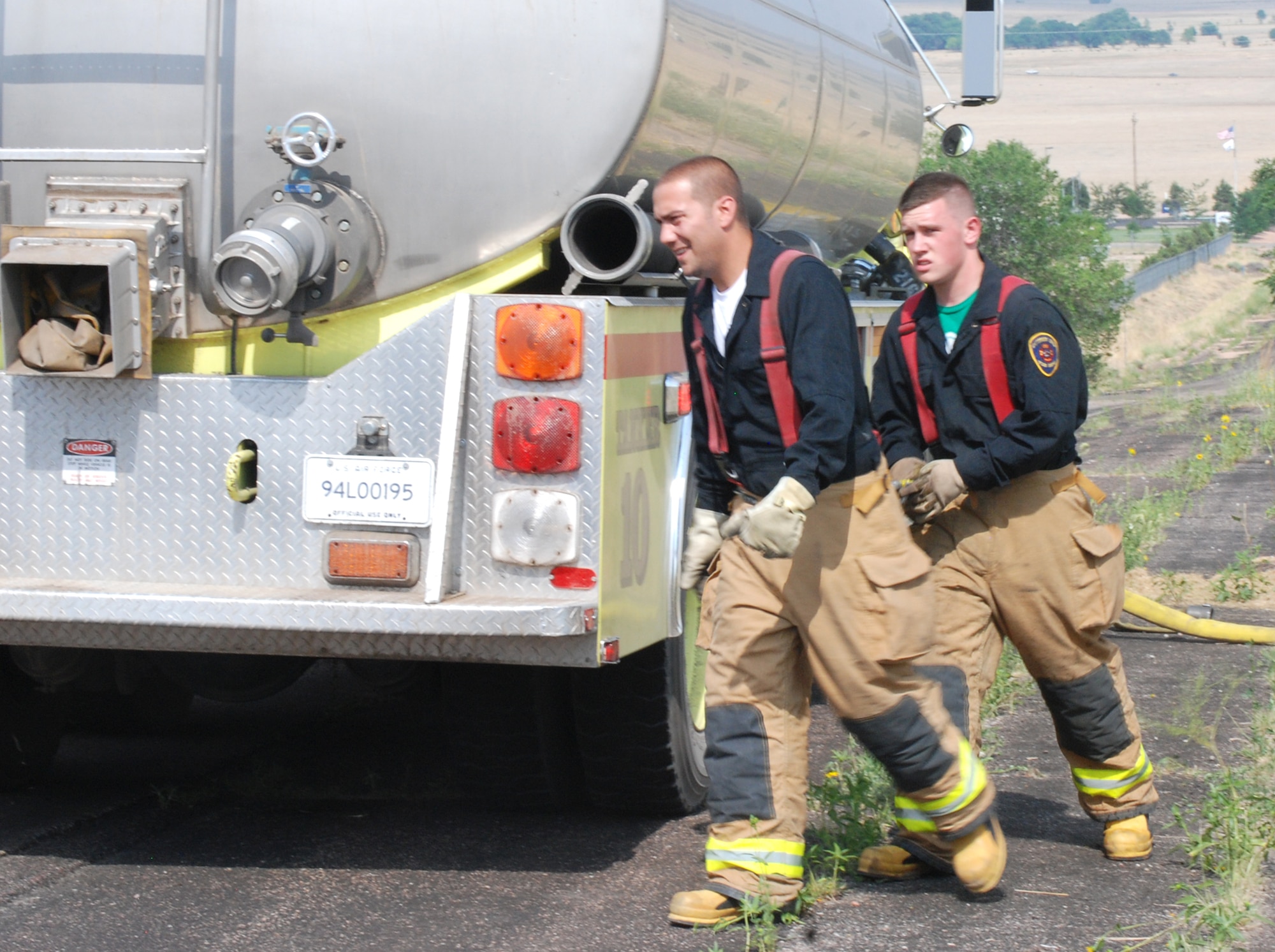 (Front to back) Staff Sgt. Daniel Bernal and Airman Adam Peterson, 21st Civil Engineer Squadron Fire Protection Flight firefighters, prepare to refill one of several fire engines responding to a fire south of the runway July 11 outside Peterson Air Force Base, Colo. The fire, which occurred outside of Peterson, required three fire departments to extinguish. Peterson firefighters are trained to suppress fires involving aircraft, buildings, automobiles and wild land. (U.S. Air Force Photo/Staff Sgt. Jessica Switzer)