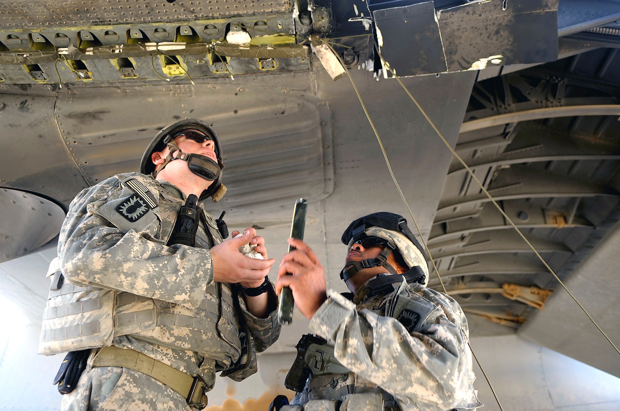 Senior Airman Anthony DeMarino, left, and Senior Master Sgt. Pervis King from the 447th Air Expeditionary Group's explosive Ordnance disposal team place a string of C-4 explosive around the wings of a C-130 Hercules aircraft that are designed to divide the plane into smaller sections so it can be moved July 7 in Baghdad, Iraq. The C-130 made an emergency landing in a field north of the Baghdad International Airport shortly after take-off on June 27. (U.S. Air Force photo/Tech. Sgt. Jeffrey Allen)