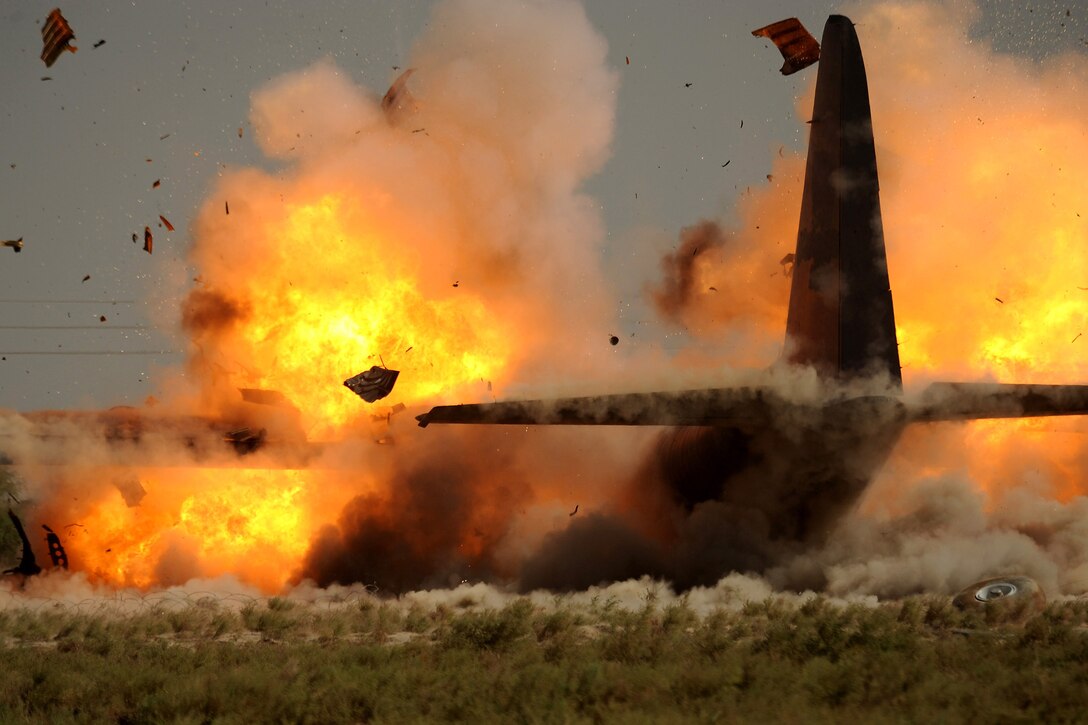 An explosive ordnance disposal team from the 447th Air Expeditionary Group detonates explosives attached to the wings of a C-130 Hercules aircraft in Iraq July 7. The aircraft was disabled after it made an emergency landing last month, and the Airmen are using a series of controlled detonations to divide the aircraft into smaller pieces so it can be moved. (U.S. Air Force photo/Tech. Sgt. Jeffrey Allen) 