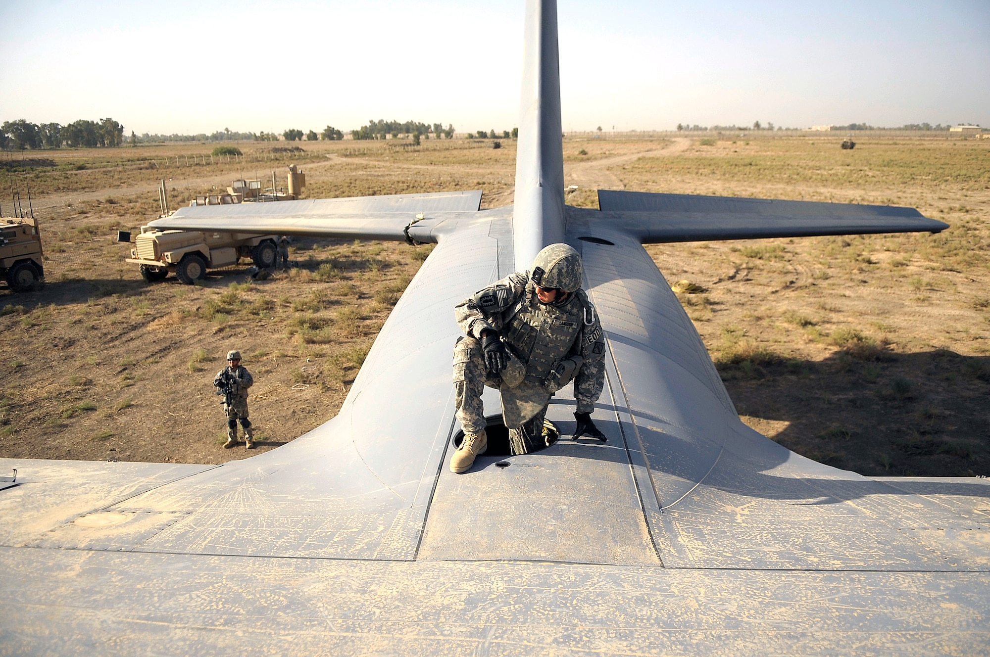 Staff Sgt. Joshua Langdon from the 447th Air Expeditionary Group's Explosive Ordinance Disposal team climbs through the top hatch of a C-130 Hercules aircraft before placing explosive charges around the wings of the plane in Baghdad, Iraq, July 7. The team is using a series of controlled detonations designed to divide the airplane into smaller pieces so it can be moved. The C-130 made an emergency landing in a field north of the Baghdad International Airport shortly after take-off on June 27. (U.S. Air Force photo/Tech. Sgt. Jeffrey Allen)