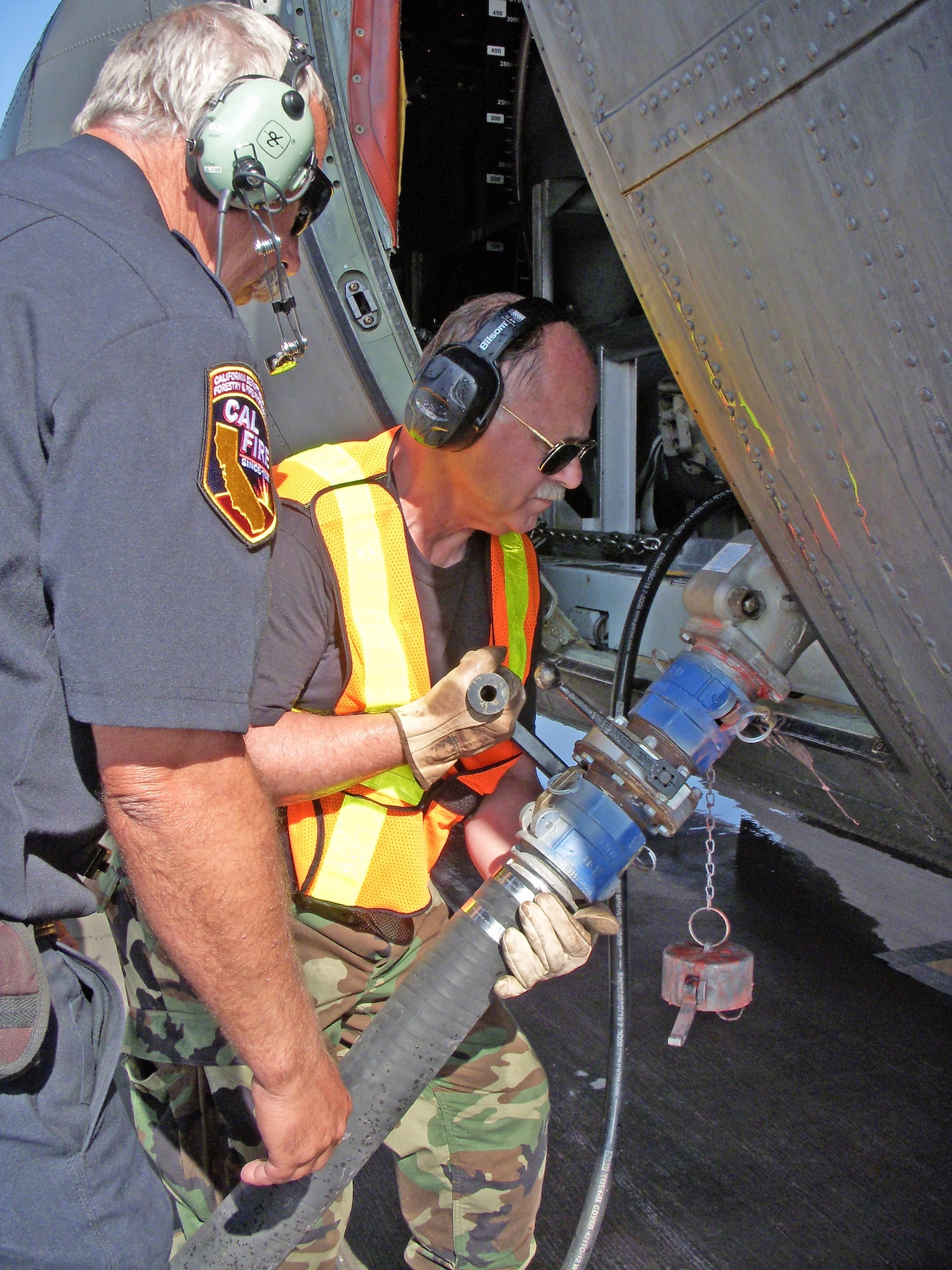 Clay Williams, a modular airborne firefighting systems specialist, and Staff Sgt. Richard Walder, with the California Air National Guard's 146th Aerial Port Squadron, connect the fire retardant loading hose to the MAFFS on a C-130 Hercules supporting the 302nd MAFFS fire retardant reload operations at Channel Islands Air National Guard Station.  (U.S. Air Force photo/Capt. Lisa Citino)