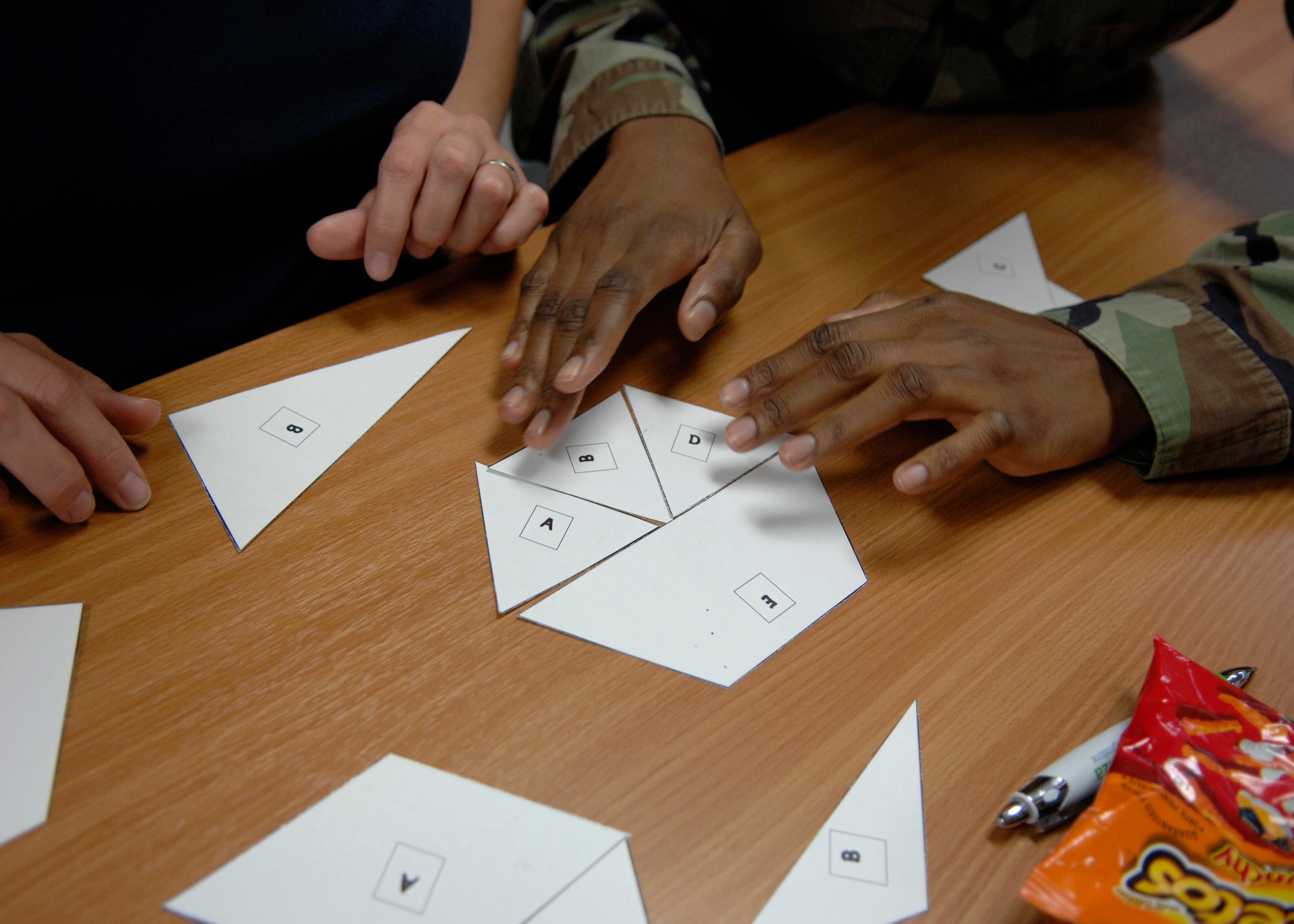 Team Holloman members participate in a silent team activity by using only body language to try and put paper shapes together as part of the Customer College Course, July 2 at the Holloman's Customer College and Training Center at Holloman Air Force Base, N.M. (U.S. Air Force photo/Airman 1st Class Rachel A. Kocin)
