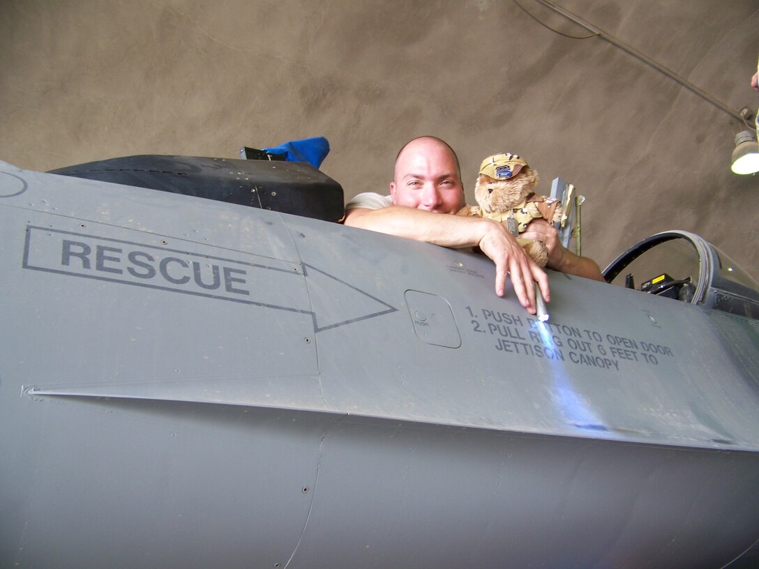 Technical Sergeant Jason Renda gets a hand inspecting the cockpit from Blabber Bear. Jason works on the ejection seat and the aircraft canopy of the F-16 fighter aircraft.  Sergeant Renda transferred to the 174th from Springfield, Ohio in 2005. This is already Jason’s second overseas deployment with the 174th. 