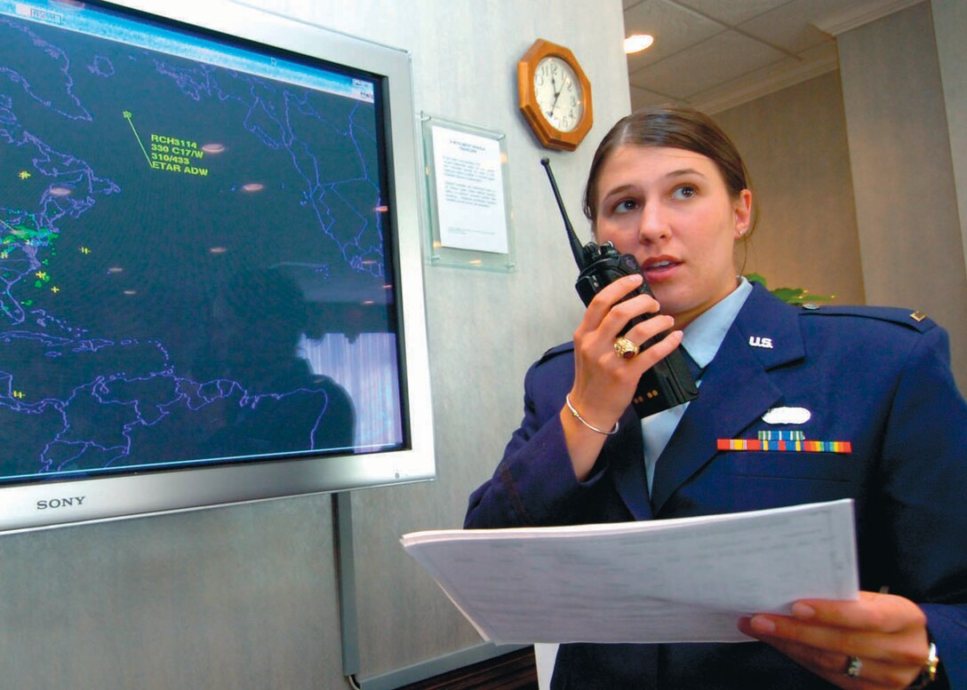 Second Lt. Hillary Hedberg, 316th Wing Protocol duty officer contacts the 316th Security Forces Squadron prior to the arrival of a large congressional delegation in the Distinguished Visitor Lounge.  A large traffic situational display monitor in the background is also a tool used to track inbound and outbound DV flights. (US Air Force/Bobby Jones)