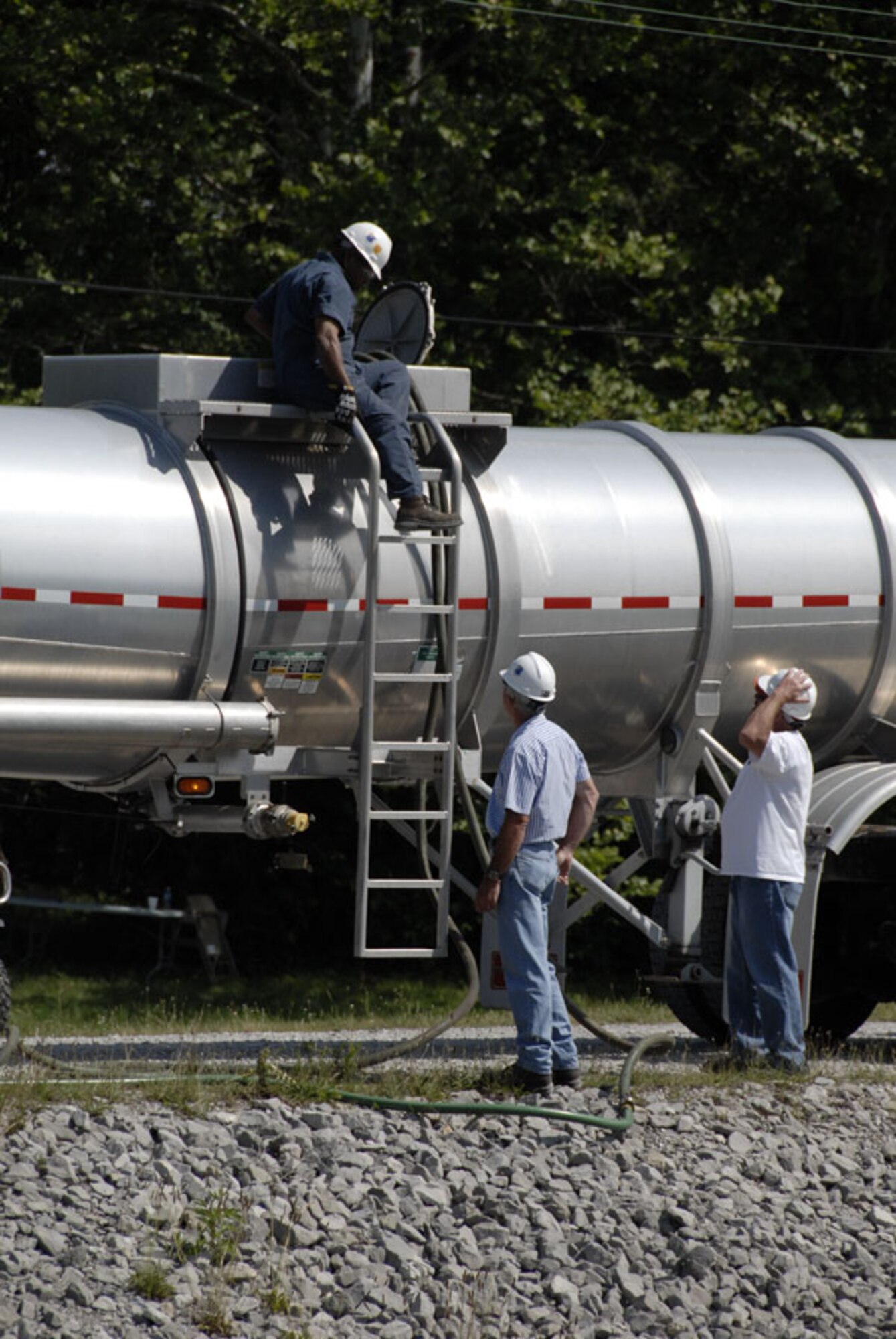 Members of Arnold Engineering Development Center's fuel spill response team at Arnold Air Force Base, Tenn., connect a hose to a 6,000 gallon capacity fuel tank truck in the proximity of the spill during the exercise. The other end of the hose is attached to a flotation device in the area of the simulated spill, and allows them to drain the fuel floating on the water’s surface. (Photo by Rick Goodfriend)