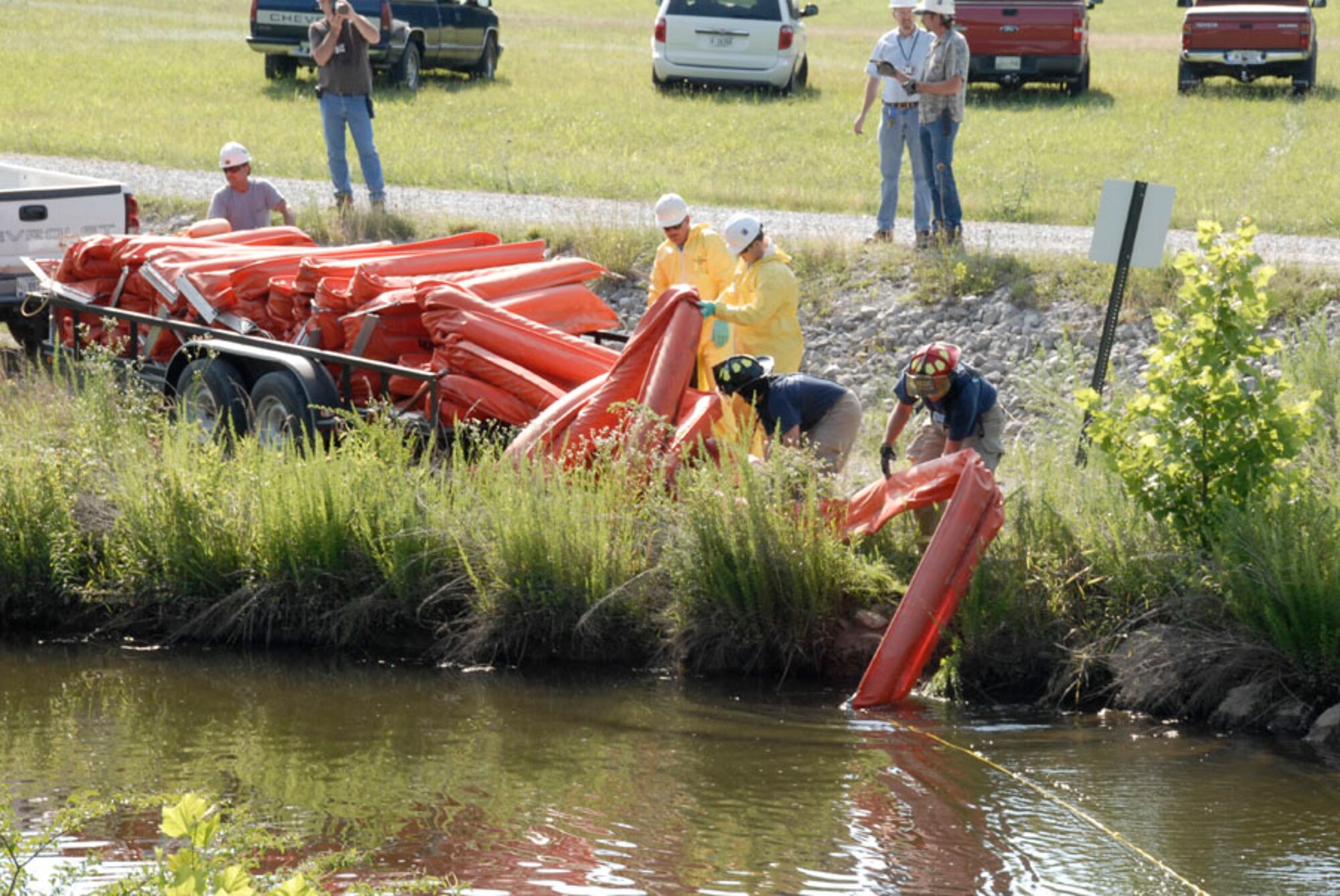 Arnold Engineering Development Center’s hazardous spill response team members, including Aerospace Testing Alliance Fire Department first responders, work to deploy a section of fuel buoys to contain a simulated fuel spill in the ditch behind pumping station number two during the June exercise at Arnold Air Force Base. (Photo by Rick Goodfriend)