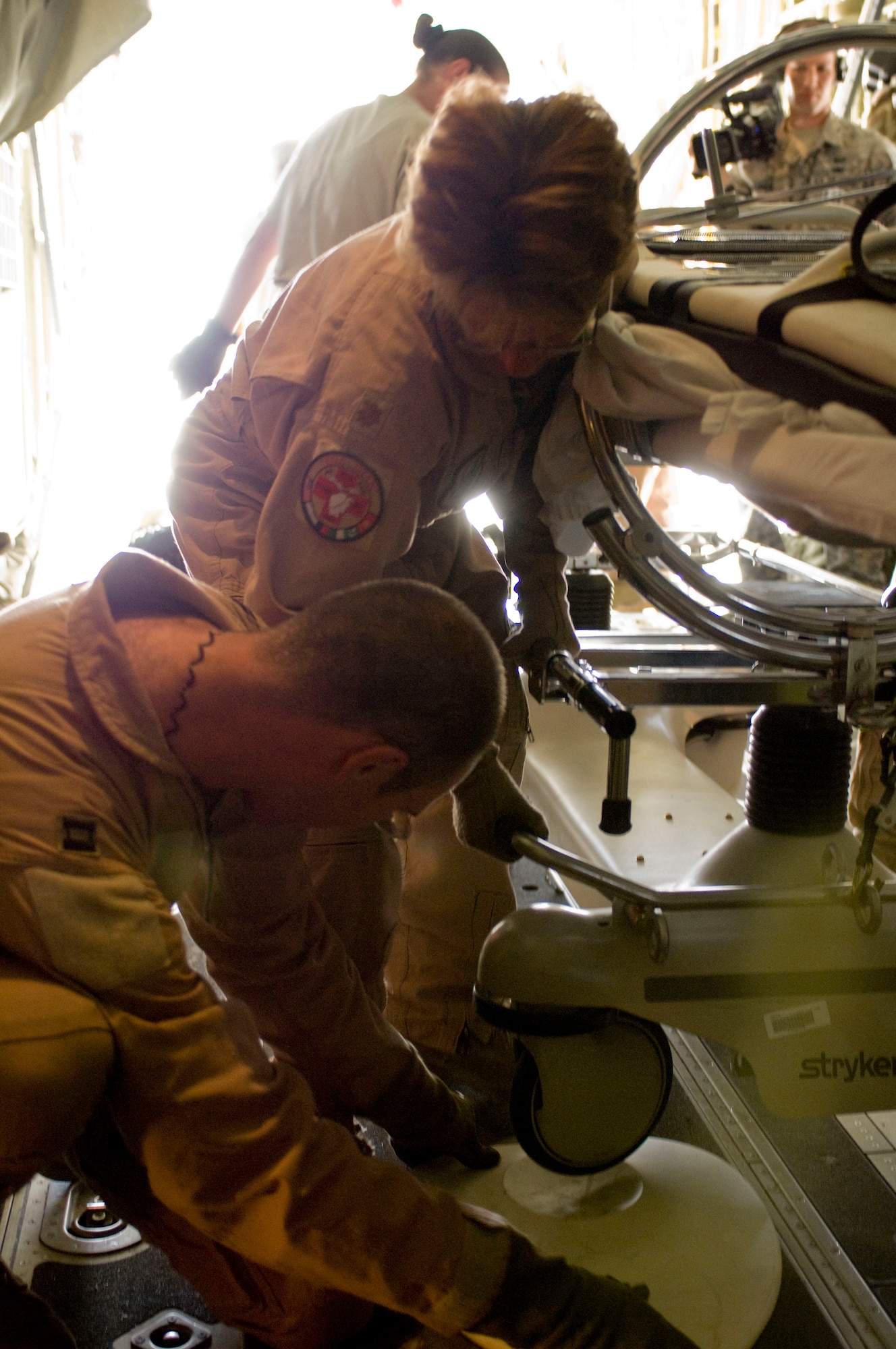 BAGRAM AIRFIELD, Afghanistan -- Maj. Julie Faubion and Capt. Matthew Rist secure a Stryker Frame to the floor of a C-130 Hercules here on July 8, 2008. This particular stretcher is made to immobilize victims of spinal injuries. Major Faubion and Captain Rist are deployed to the 455th Expeditionary Aeromedical Evacuation Flight here from the 375th Aeromedical Evacuation Squadron, Scott Air Force Base, Ill. (U.S. Air Force photo by Staff Sgt. Samuel Morse)