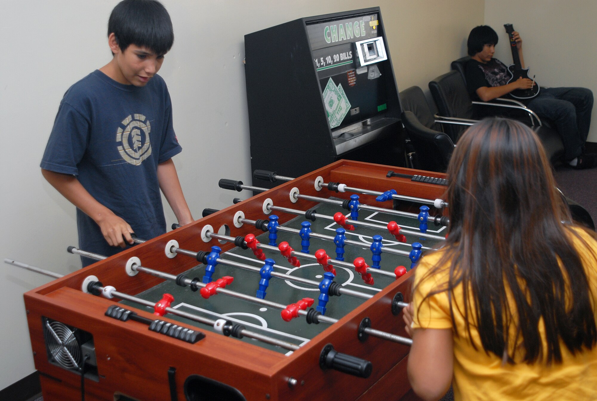 Angel Sepulveda (left) plays foosball with his sister Alexandra while their brother plays “Guitar Hero” at the Schilling Community Center Thursday. (U.S. Air Force photo/Staff Sgt. Christopher Marasky)