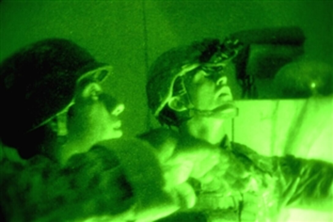 As seen through a night vision lens, U.S. Army Staff Sgt. Phillip Evans, right, searches a home in the Rusafa security district of eastern Baghdad, Iraq, with an Iraqi National policeman during a night patrol, June 30, 2008. Evans is assigned to the 89th Cavalry Regiment's Troop C, 3rd Squadron. 