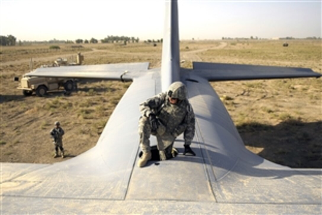 U.S. Air Force Staff Sgt. Joshua Langdon climbs through the top hatch of a C-130 Hercules aircraft before placing explosive charges around the wings of the plane in Baghdad, Iraq, July 7, 2008. Langdon and his team are using a series of controlled detonations designed to divide the airplane into smaller pieces so it can be moved. The airmen are assigned to the 447th Air Expeditionary Group.

