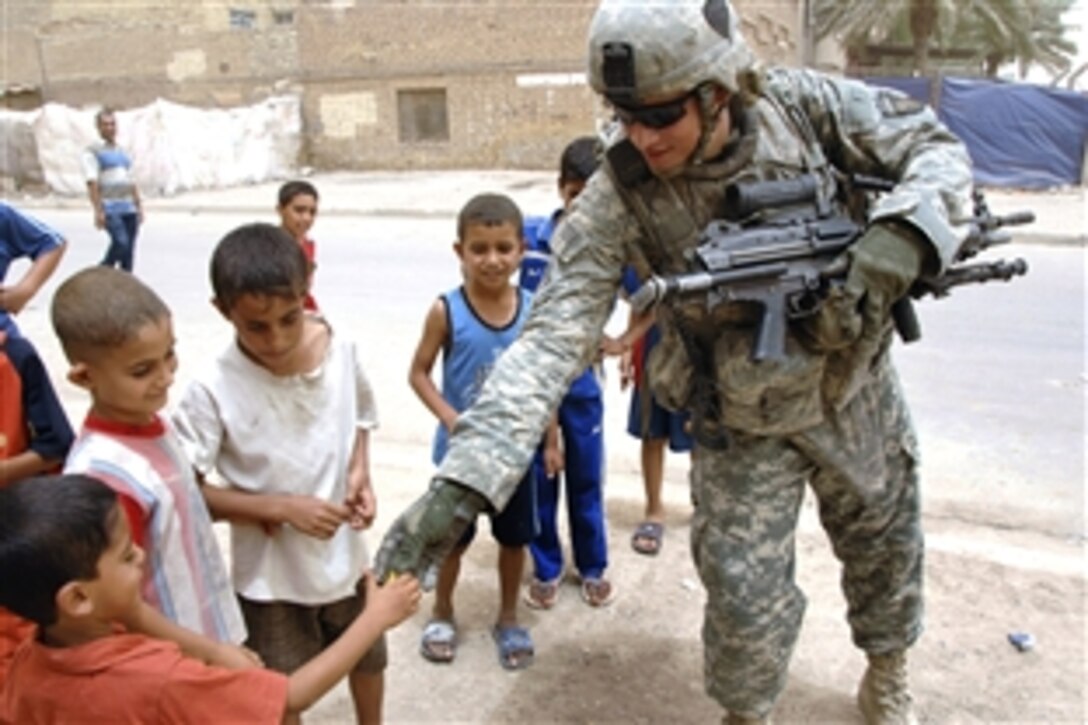 A U.S. Army soldier hands candy to a local boy during a patrol in Baghdad, Iraq, July 8, 2008. The soldier is assigned to the 101st Airborne Division's Troop B, 1st Squadron, 75th Cavalry Regiment. 